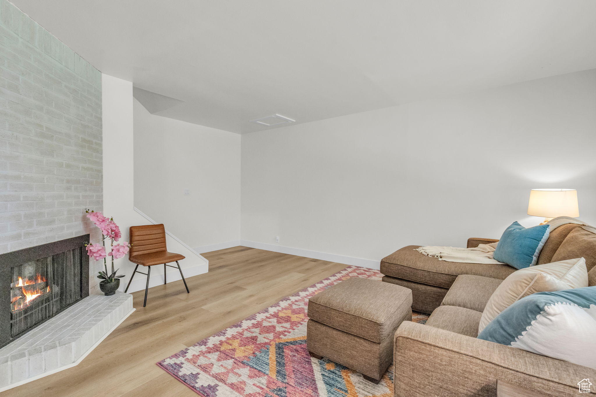 Living room with light hardwood / wood-style flooring and a brick fireplace