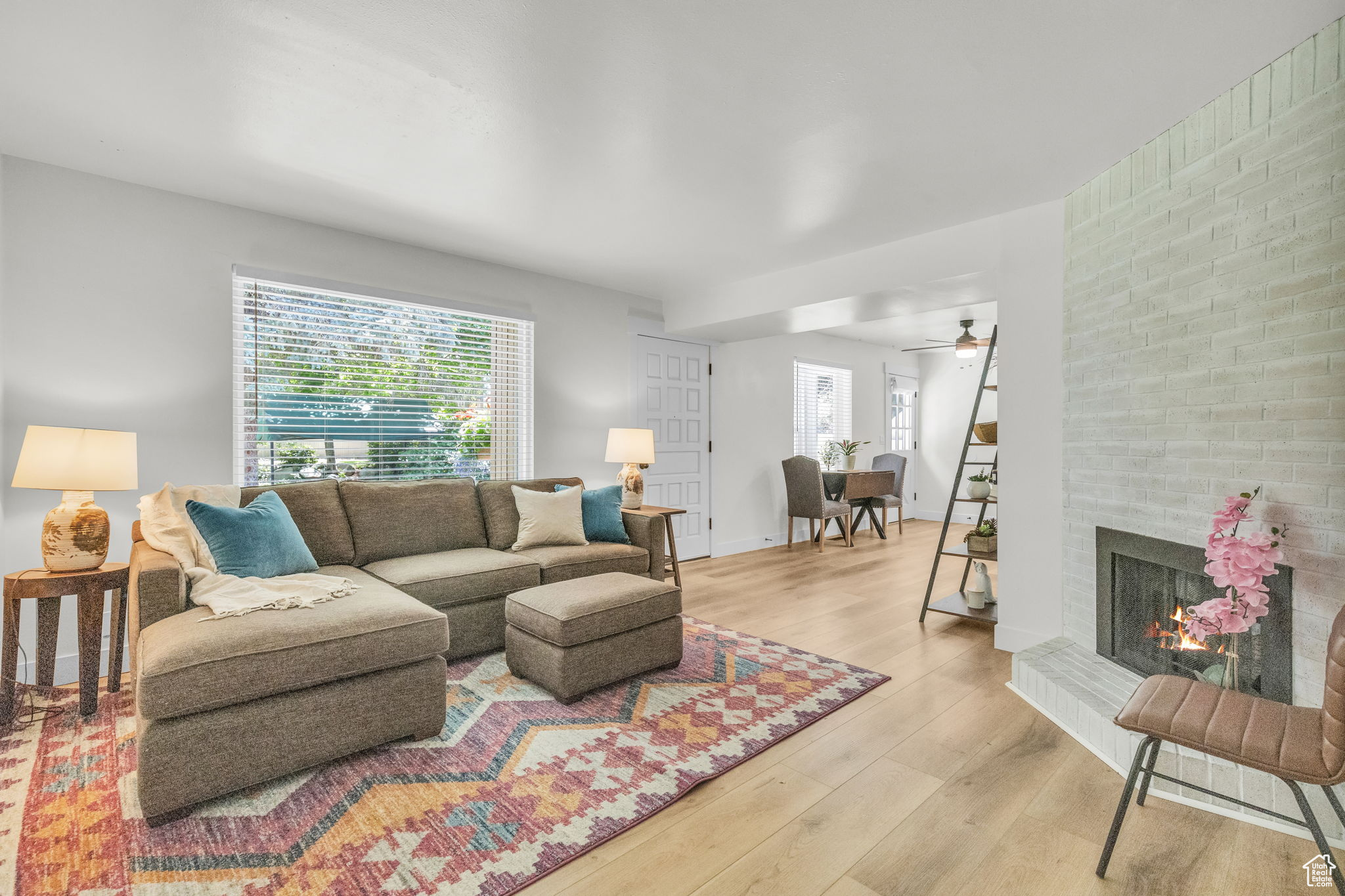 Living room featuring plenty of natural light, ceiling fan, light hardwood / wood-style floors, and a brick fireplace