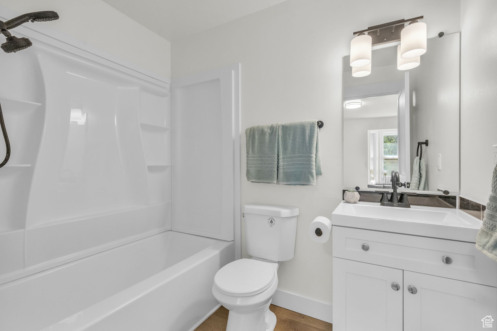 Full bathroom featuring hardwood / wood-style floors, oversized vanity, toilet, and shower / bathtub combination