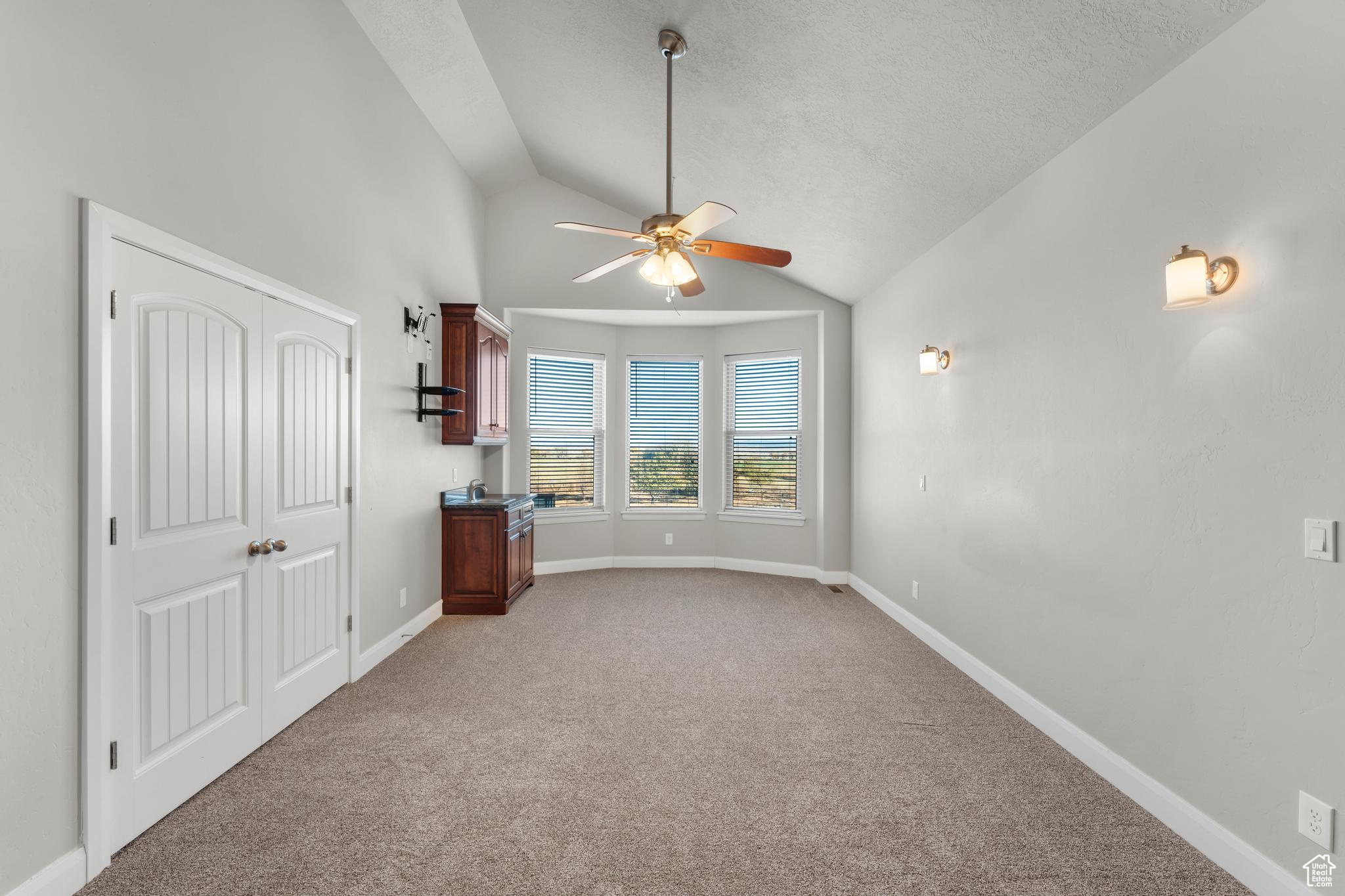 Master bedroom featuring lofted ceiling, ceiling fan, a textured ceiling, and light carpet