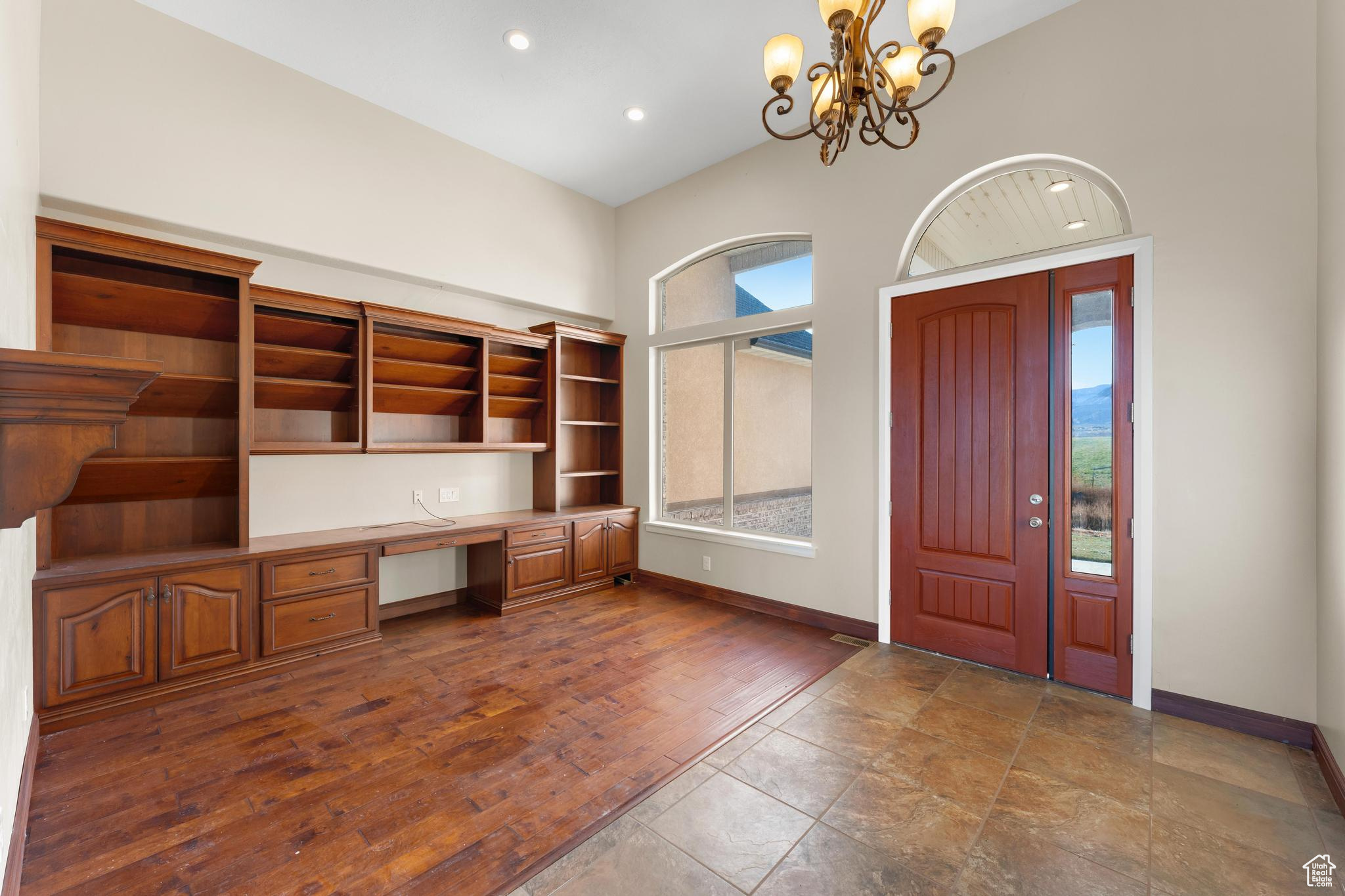 Tiled foyer featuring lofted ceiling and a notable chandelier