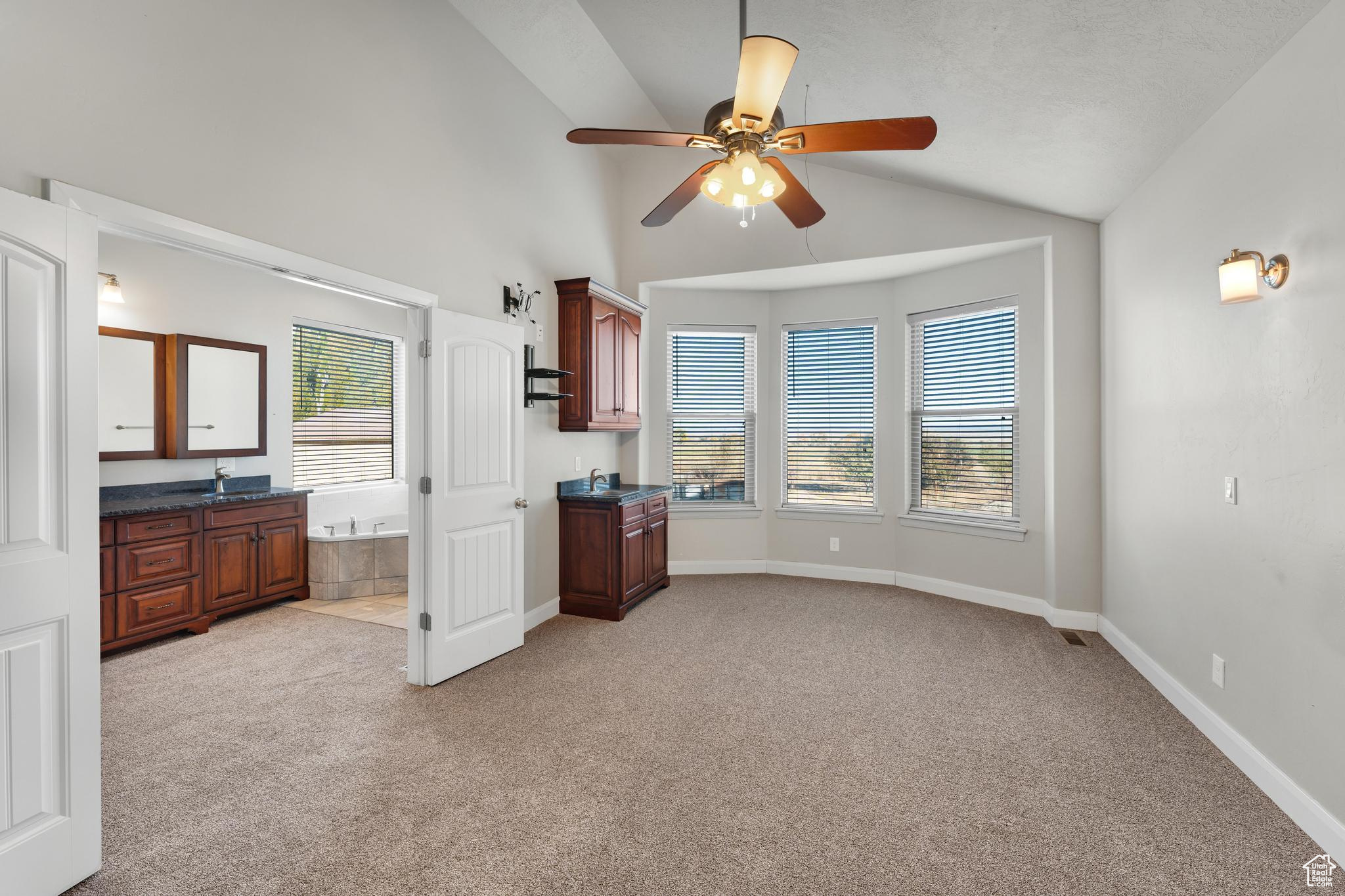 Master bedroom featuring a healthy amount of sunlight, lofted ceiling, light carpet, and ceiling fan