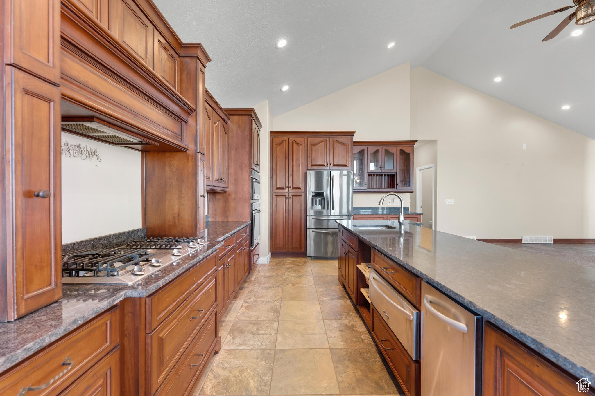 Kitchen featuring light tile floors, sink, premium range hood, appliances with stainless steel finishes, and ceiling fan