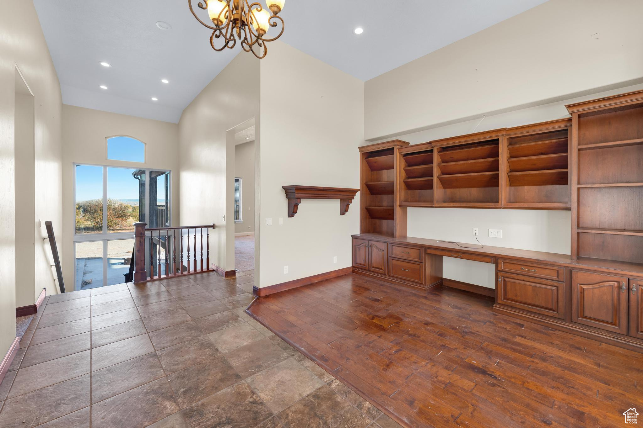 Interior space featuring dark wood-type flooring, an inviting chandelier, and high vaulted ceiling