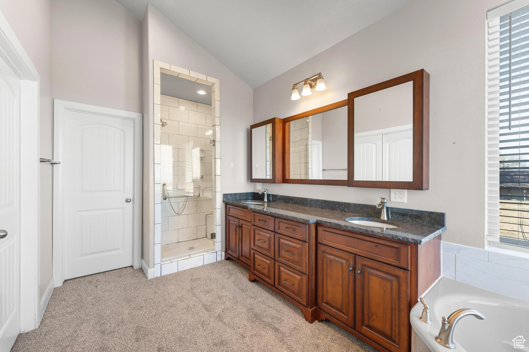 Master bathroom with lofted ceiling, independent shower and bath, and double vanity