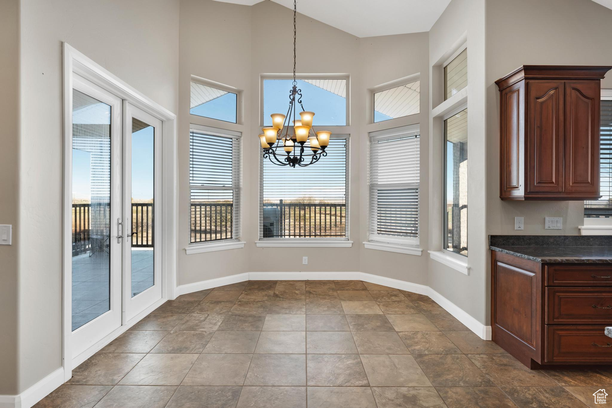 Dining area featuring dark tile floors, french doors, and a chandelier