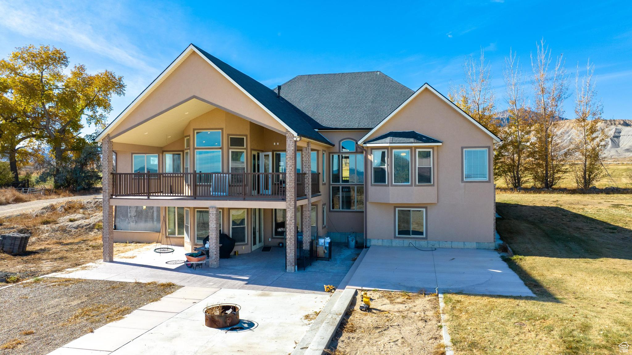 View of back of property with a patio, balcony, and fire pit