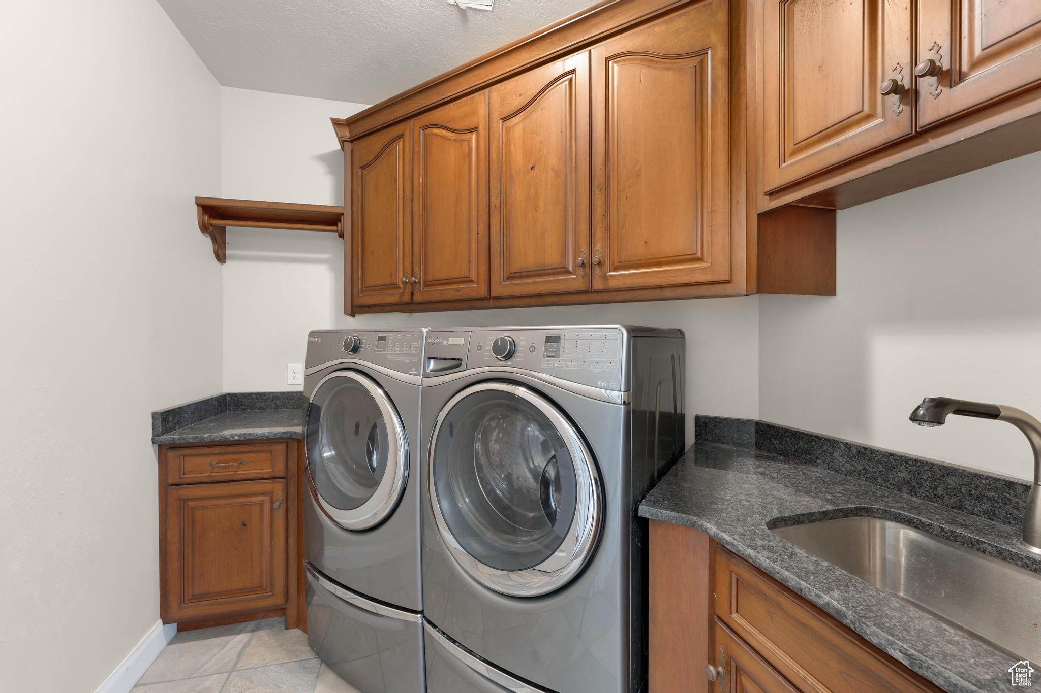 Washroom with cabinets, sink, independent washer and dryer, and light tile floors