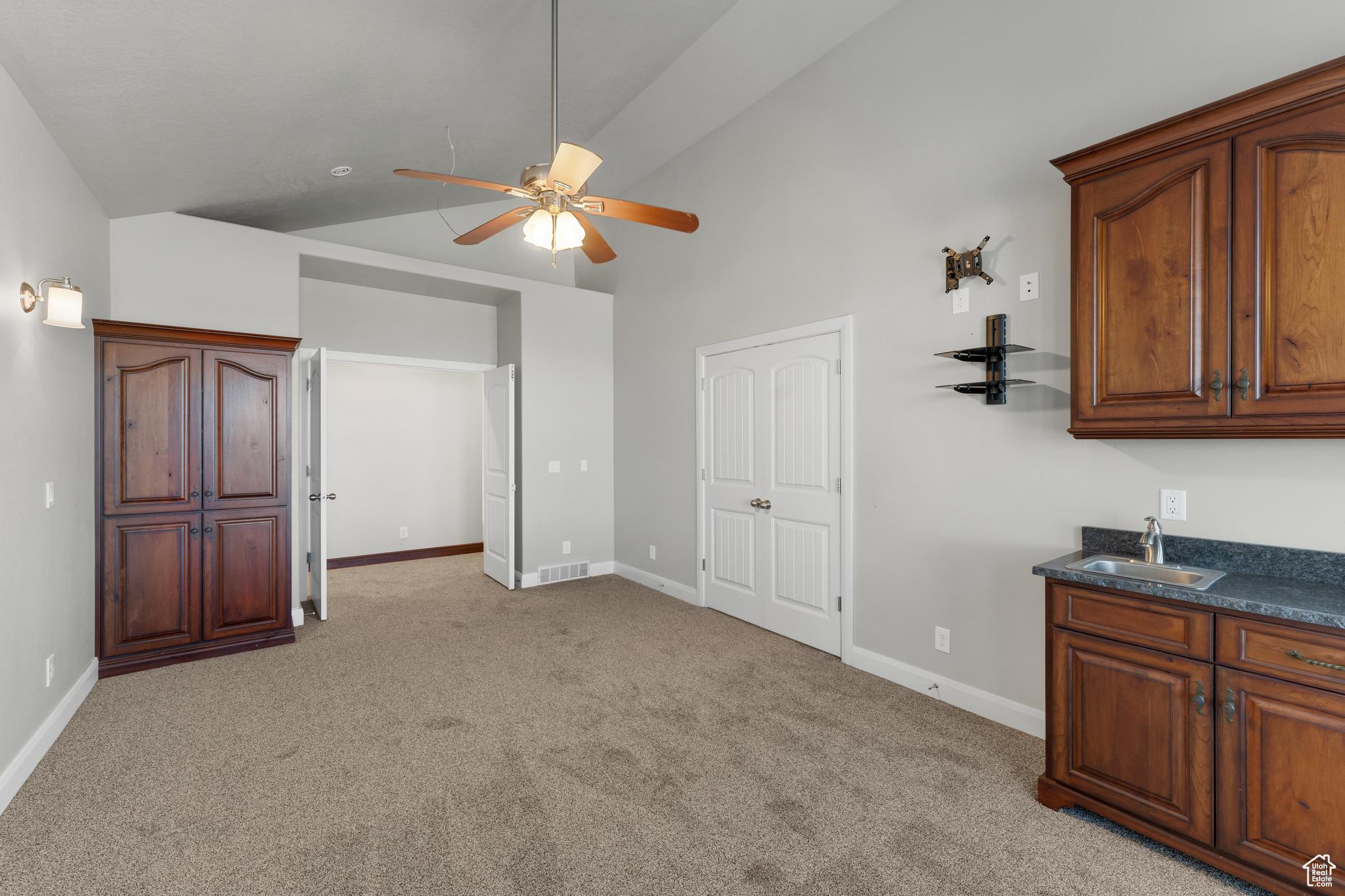 Master bedroom with ceiling fan, sink, vaulted ceiling, and light colored carpet