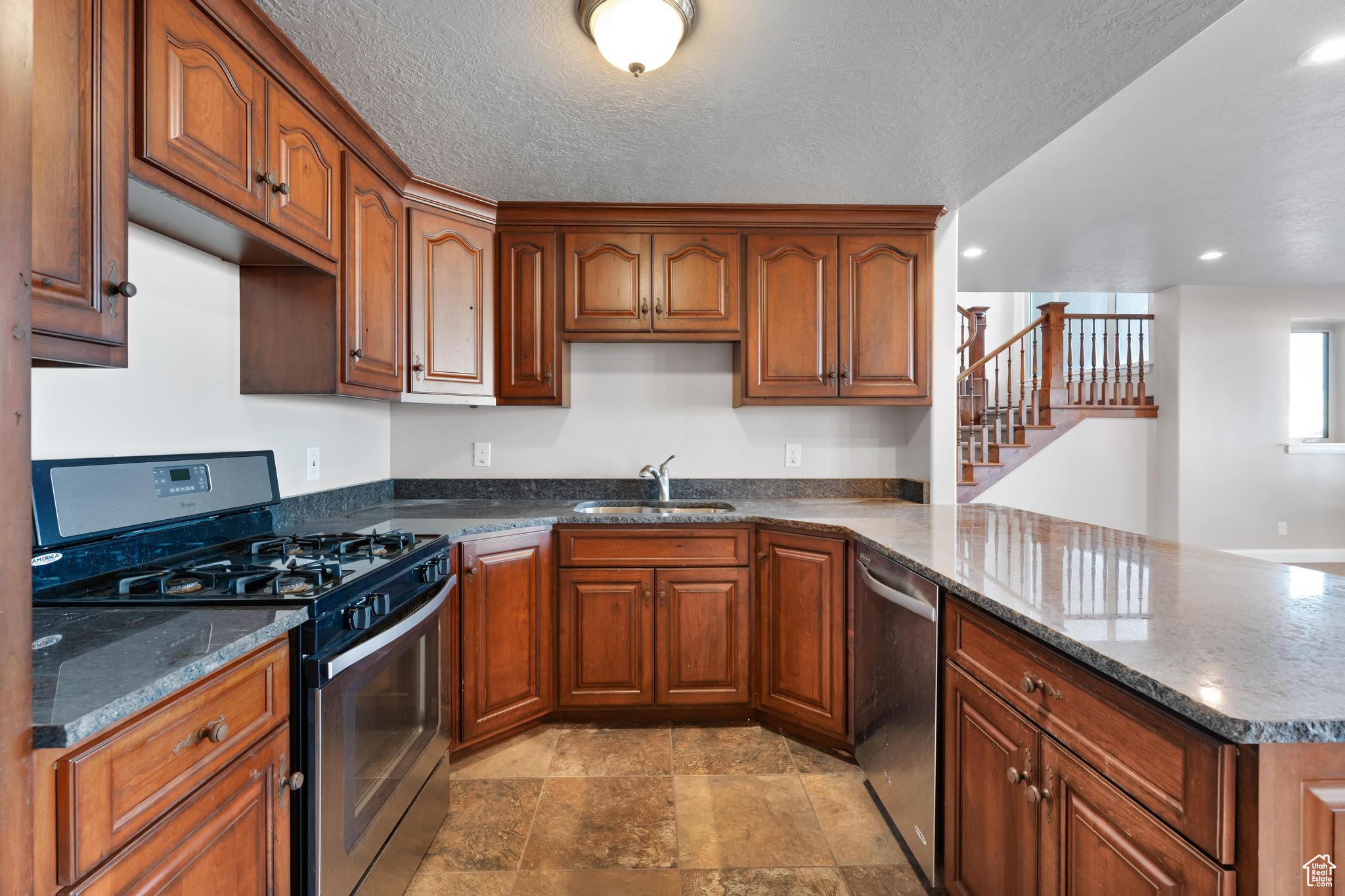 Amazing full second kitchen in the basement, featuring full gas range, dishwasher, sink, and large island bar.