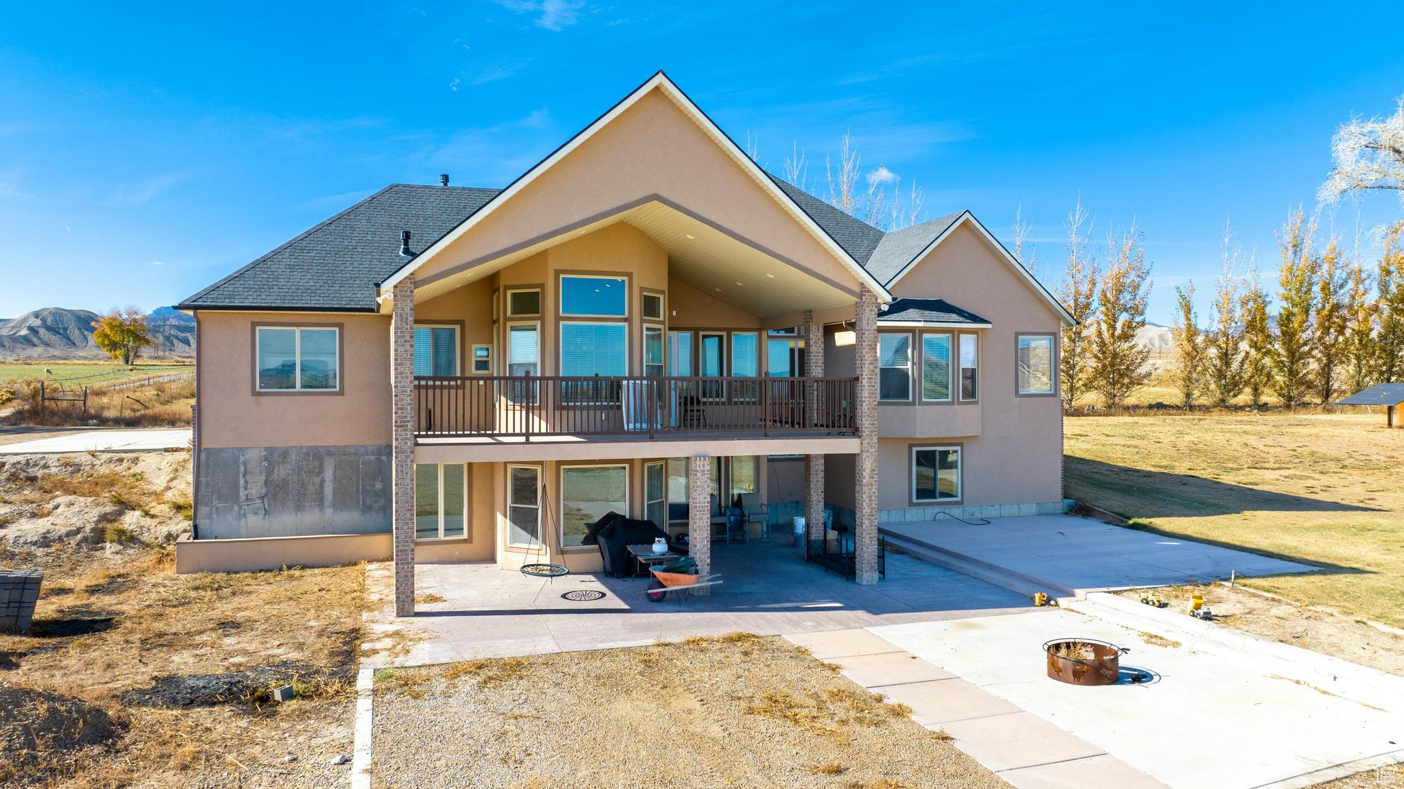 View of back of home with a patio area, a balcony, and a fire pit