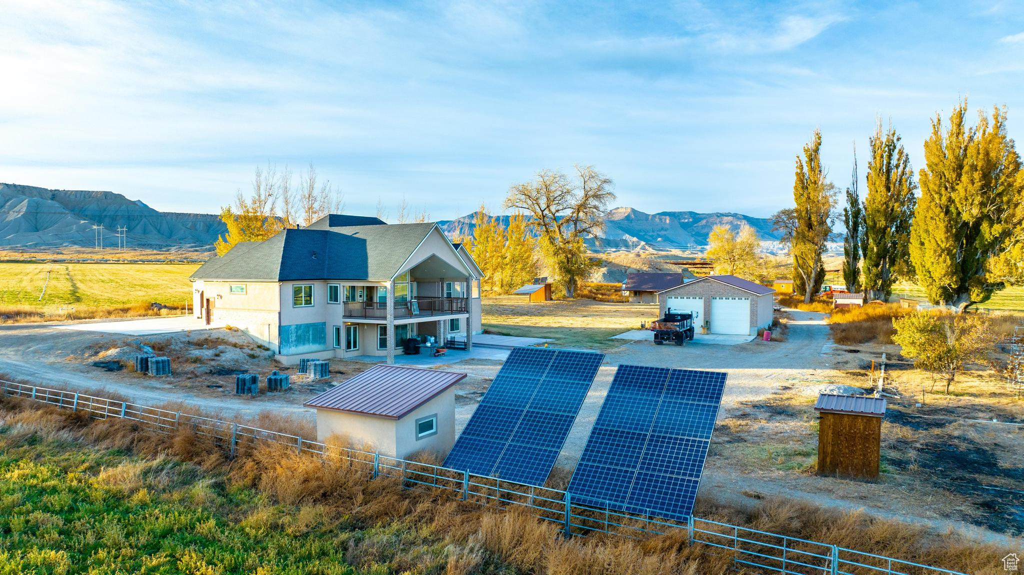 Back of house with solar panels, a balcony, a rural view, and a mountain view