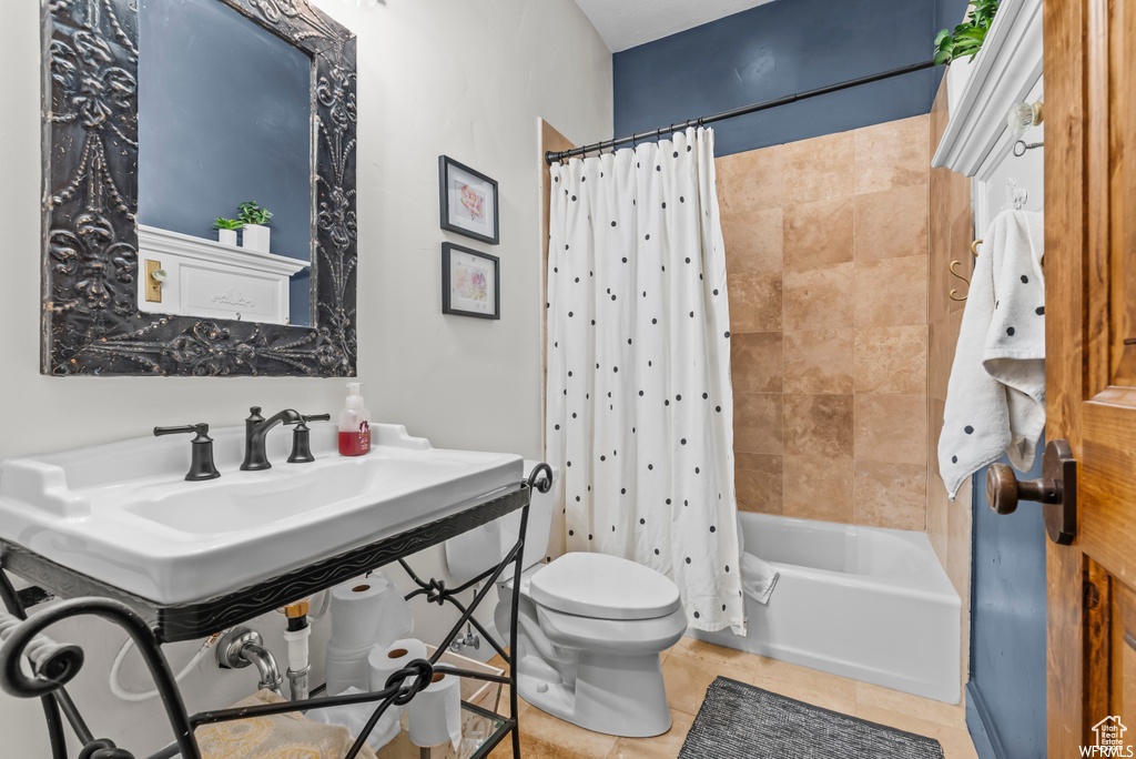 Bathroom featuring tile floors, shower / tub combo with curtain, and toilet