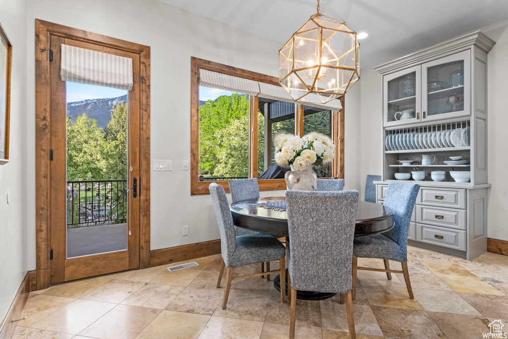 Dining room featuring a healthy amount of sunlight, an inviting chandelier, and light tile flooring