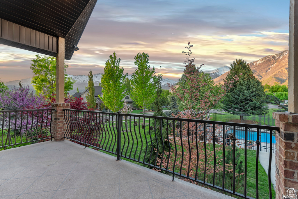 Balcony at dusk featuring a mountain view and a fenced in pool