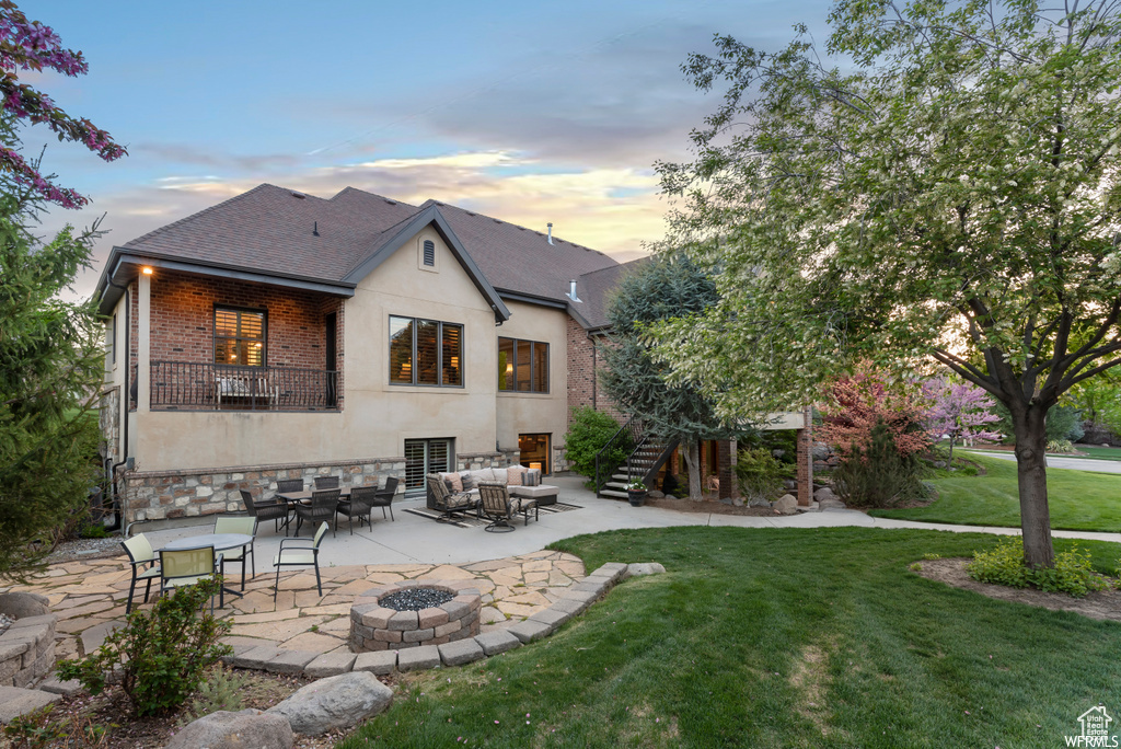 Back house at dusk featuring a yard, an outdoor fire pit, and a patio