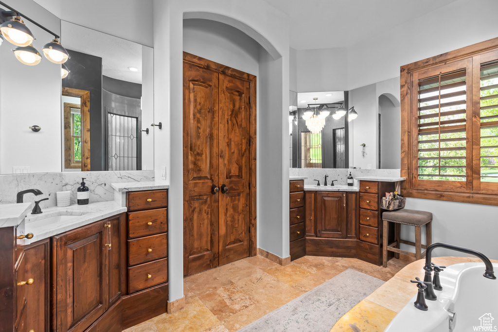 Bathroom featuring tile floors, dual bowl vanity, backsplash, and a tub