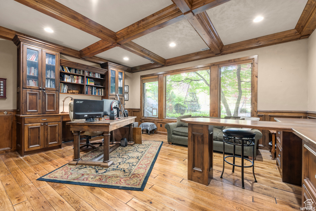 Office area featuring built in desk, coffered ceiling, beam ceiling, and light hardwood / wood-style flooring