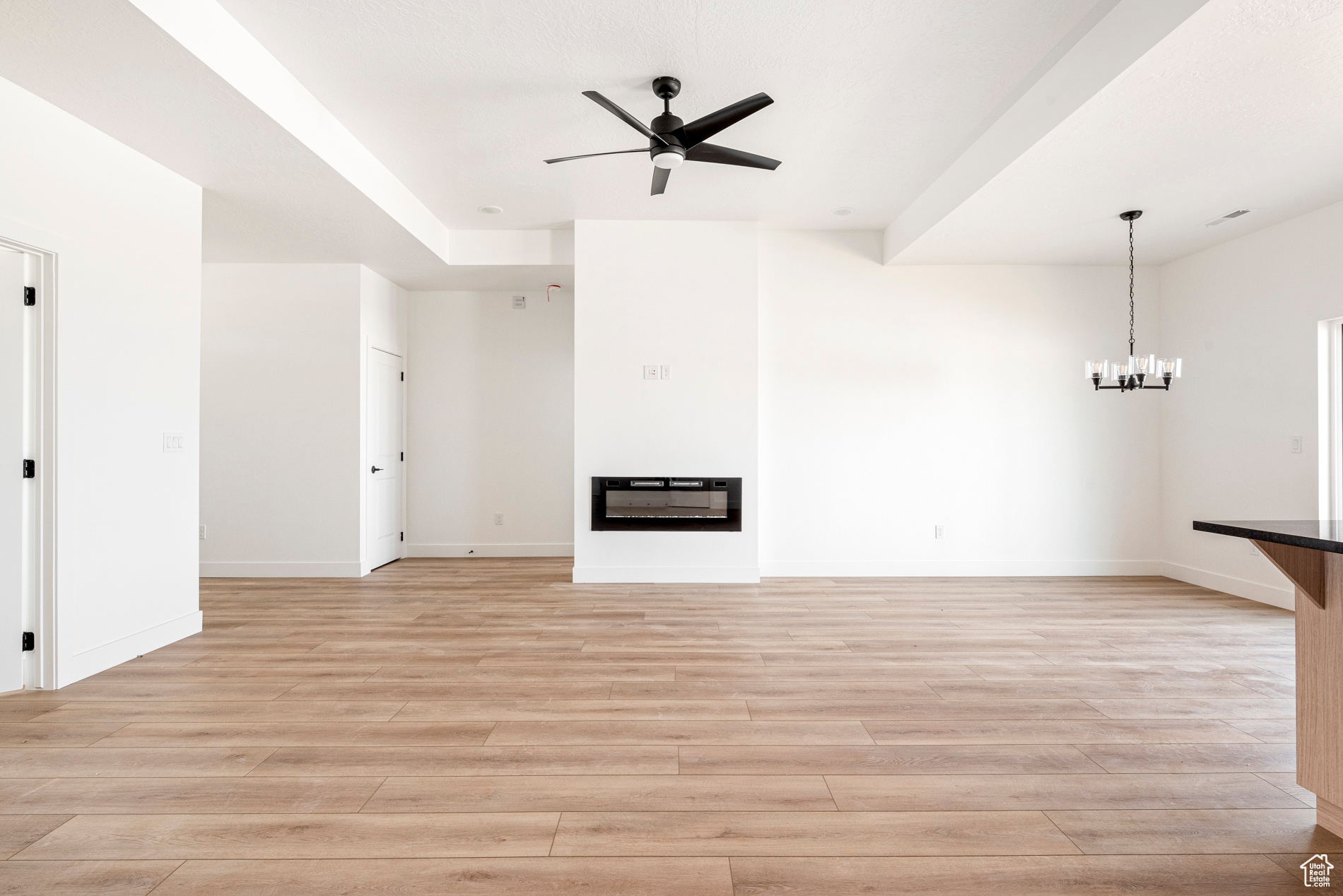 Unfurnished living room featuring light hardwood / wood-style flooring and ceiling fan with notable chandelier