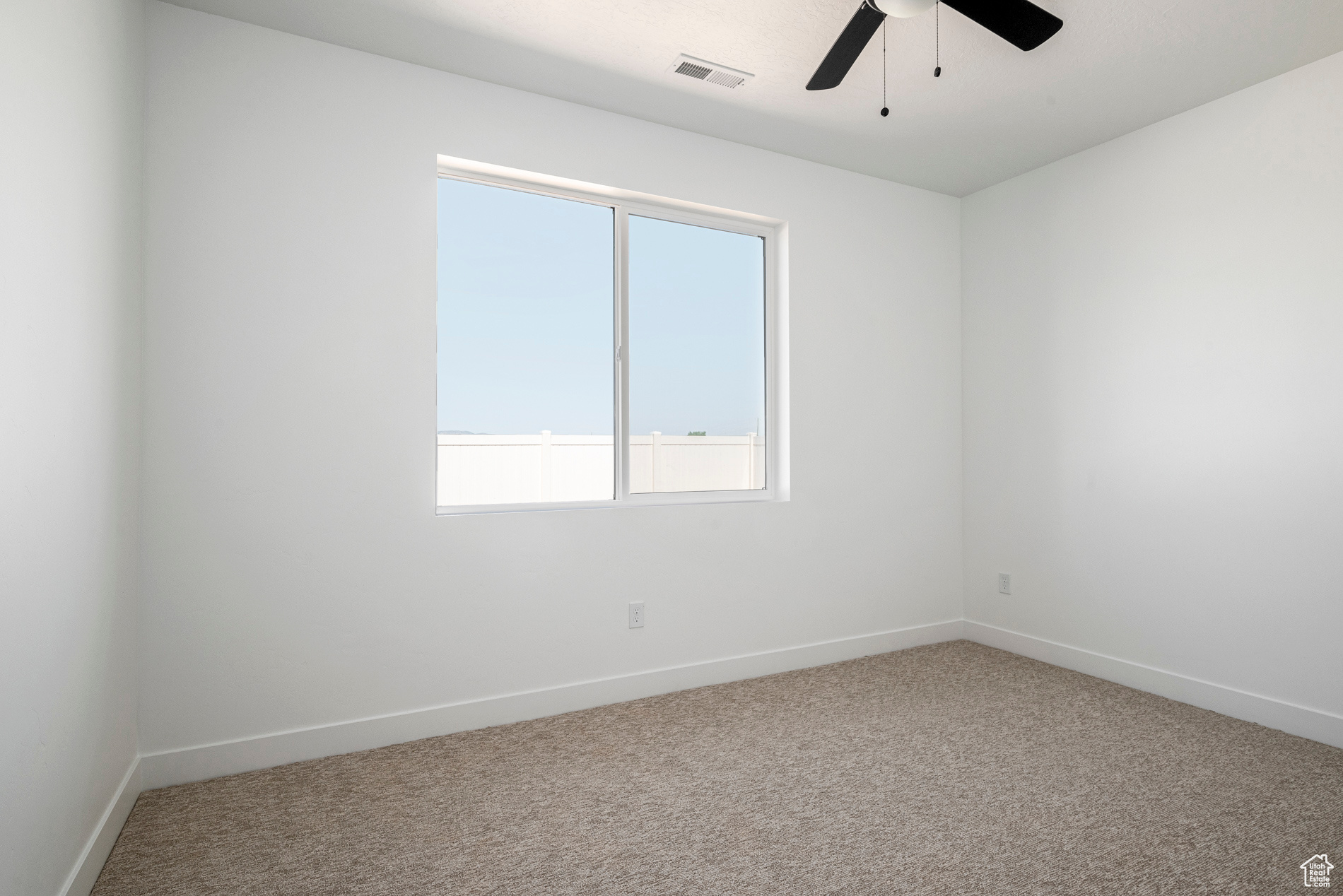 Carpeted empty room featuring ceiling fan