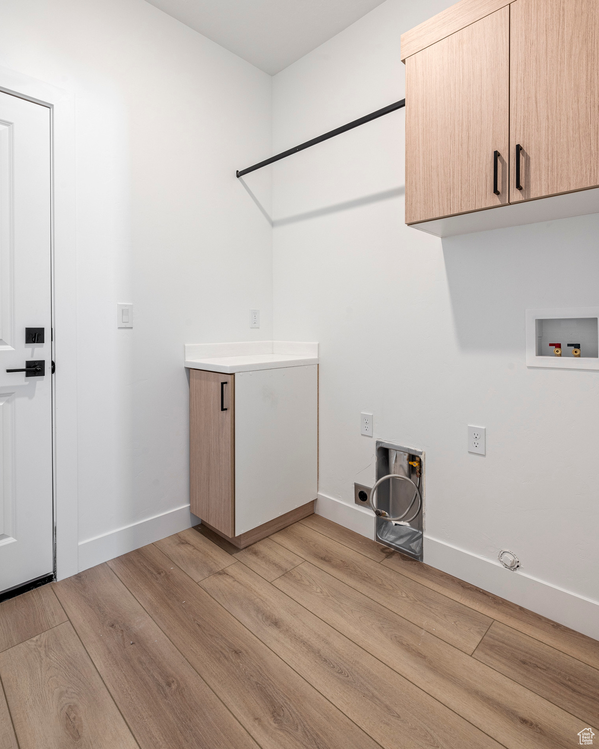 Laundry area featuring electric dryer hookup, light wood-type flooring, cabinets, and hookup for a washing machine