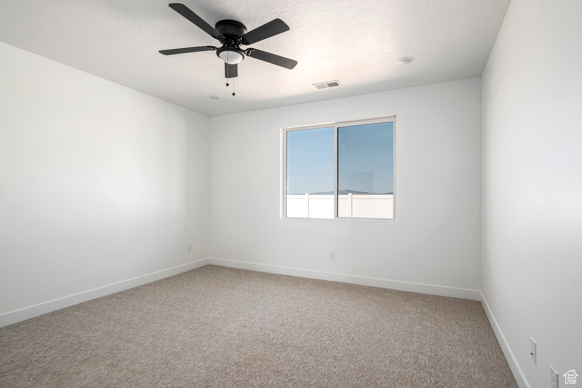 Carpeted empty room featuring ceiling fan