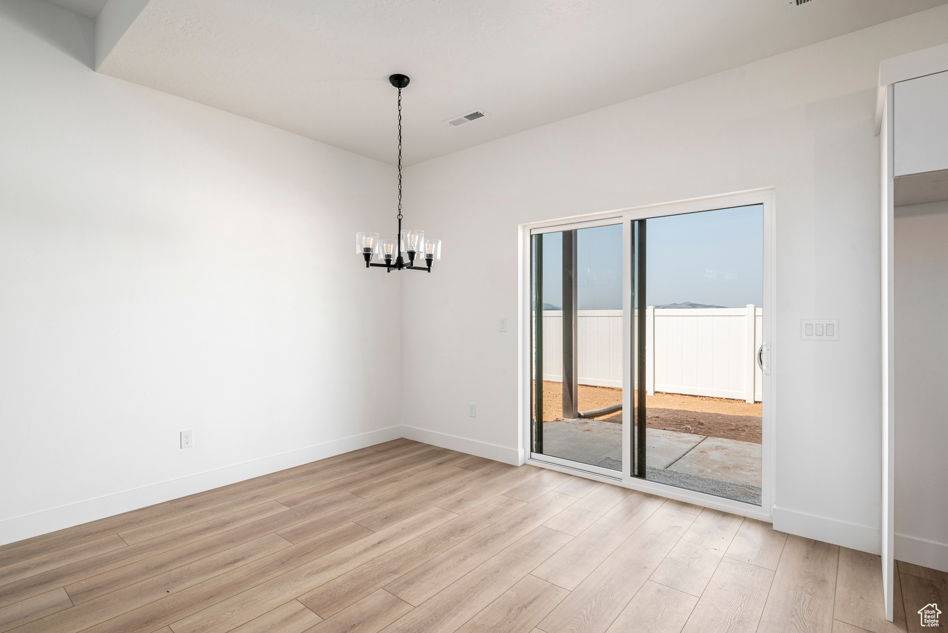 Unfurnished room featuring light hardwood / wood-style flooring and a chandelier