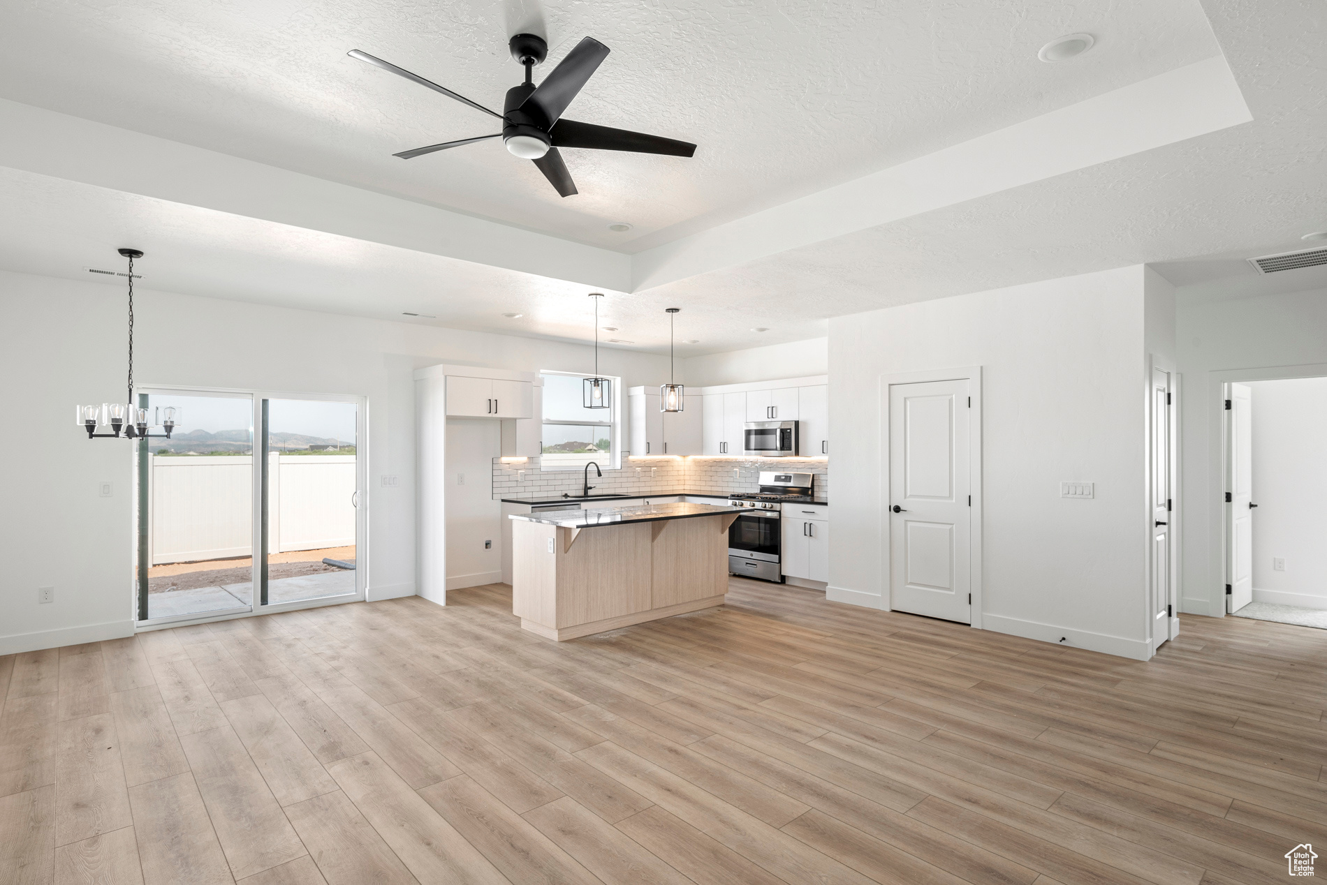 Kitchen with appliances with stainless steel finishes, white cabinets, light wood-type flooring, and a kitchen island