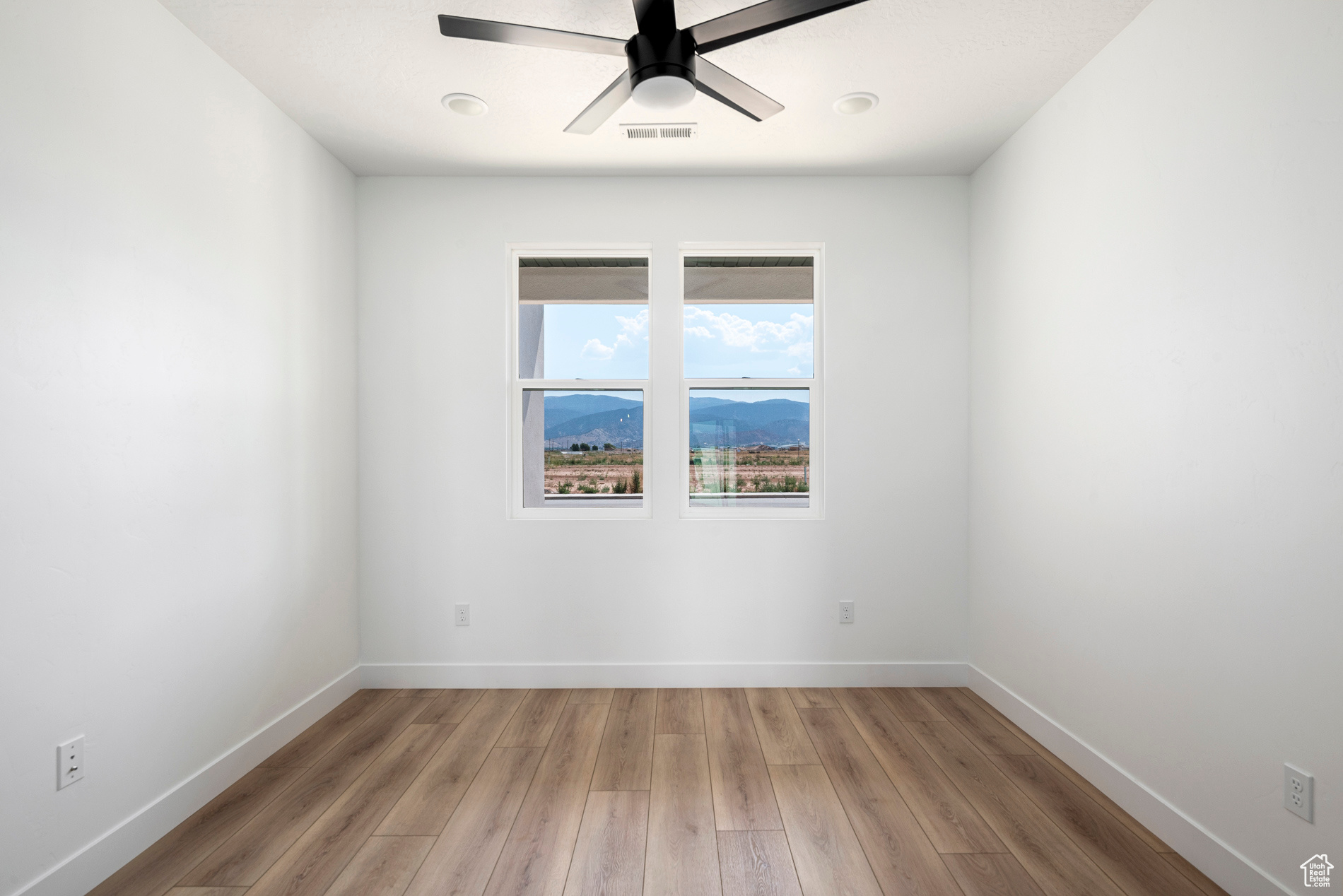 Unfurnished room with ceiling fan, a mountain view, and hardwood / wood-style floors