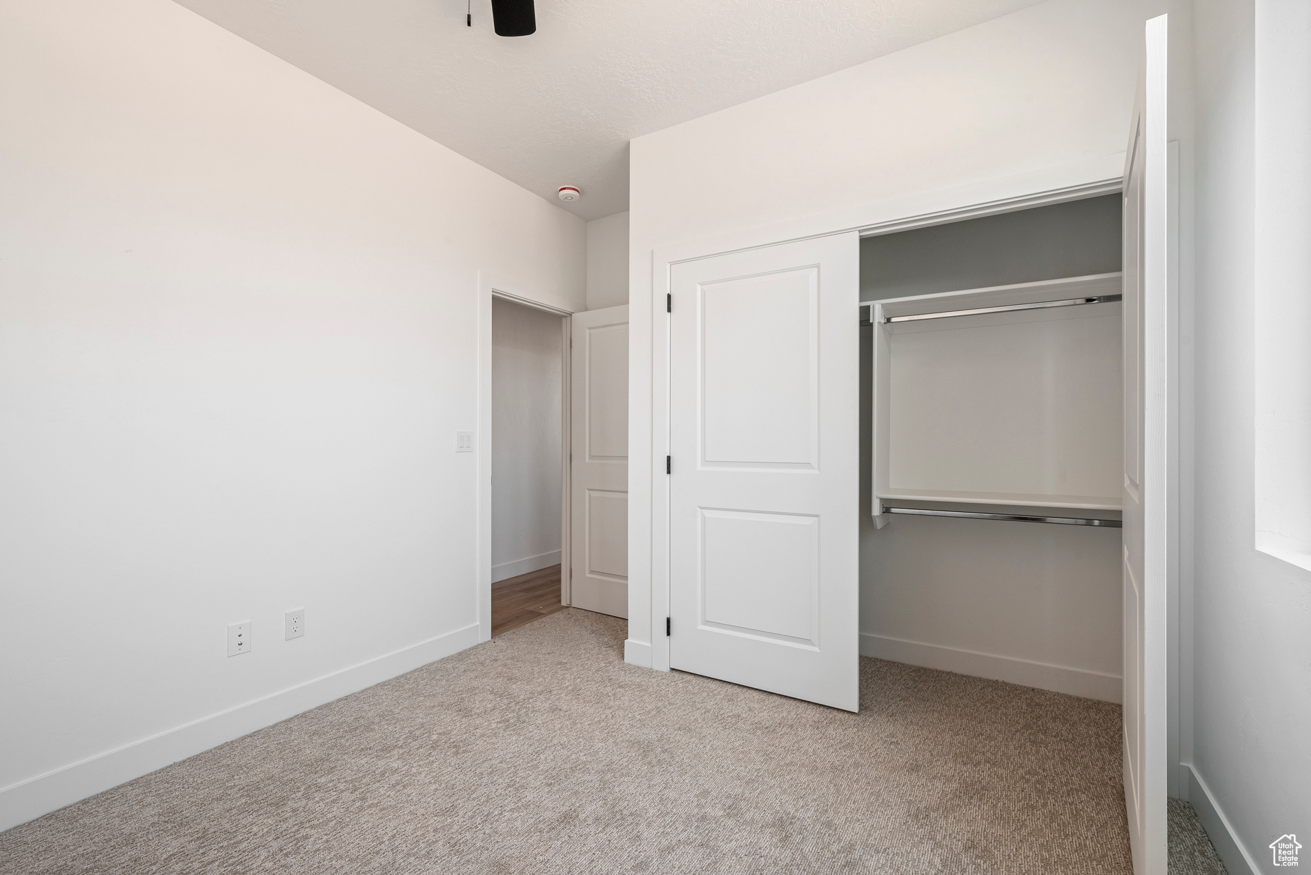 Unfurnished bedroom featuring ceiling fan, a closet, and light colored carpet