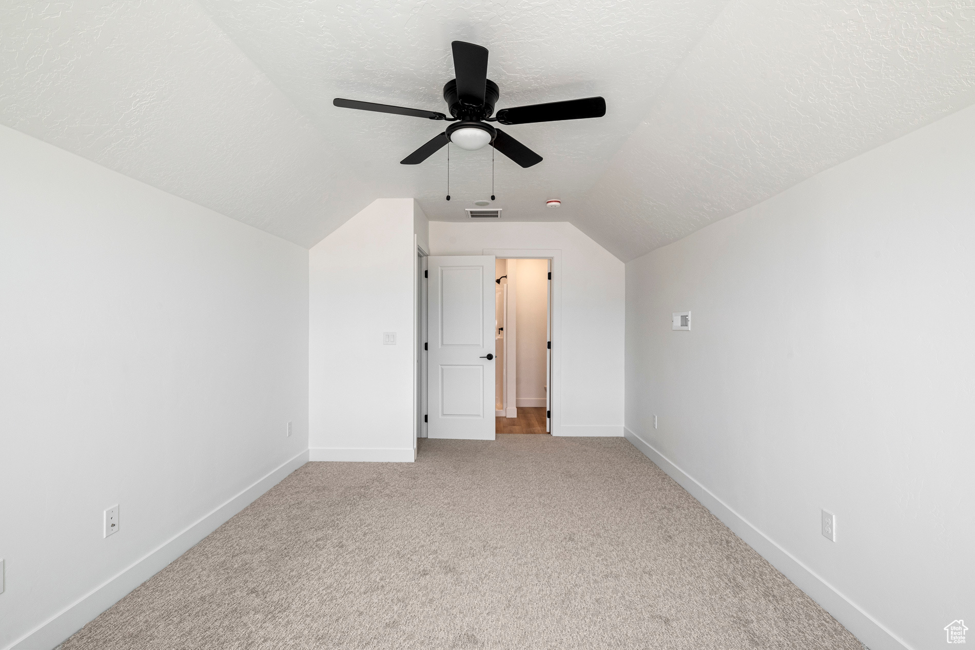 Additional living space with carpet, ceiling fan, vaulted ceiling, and a textured ceiling