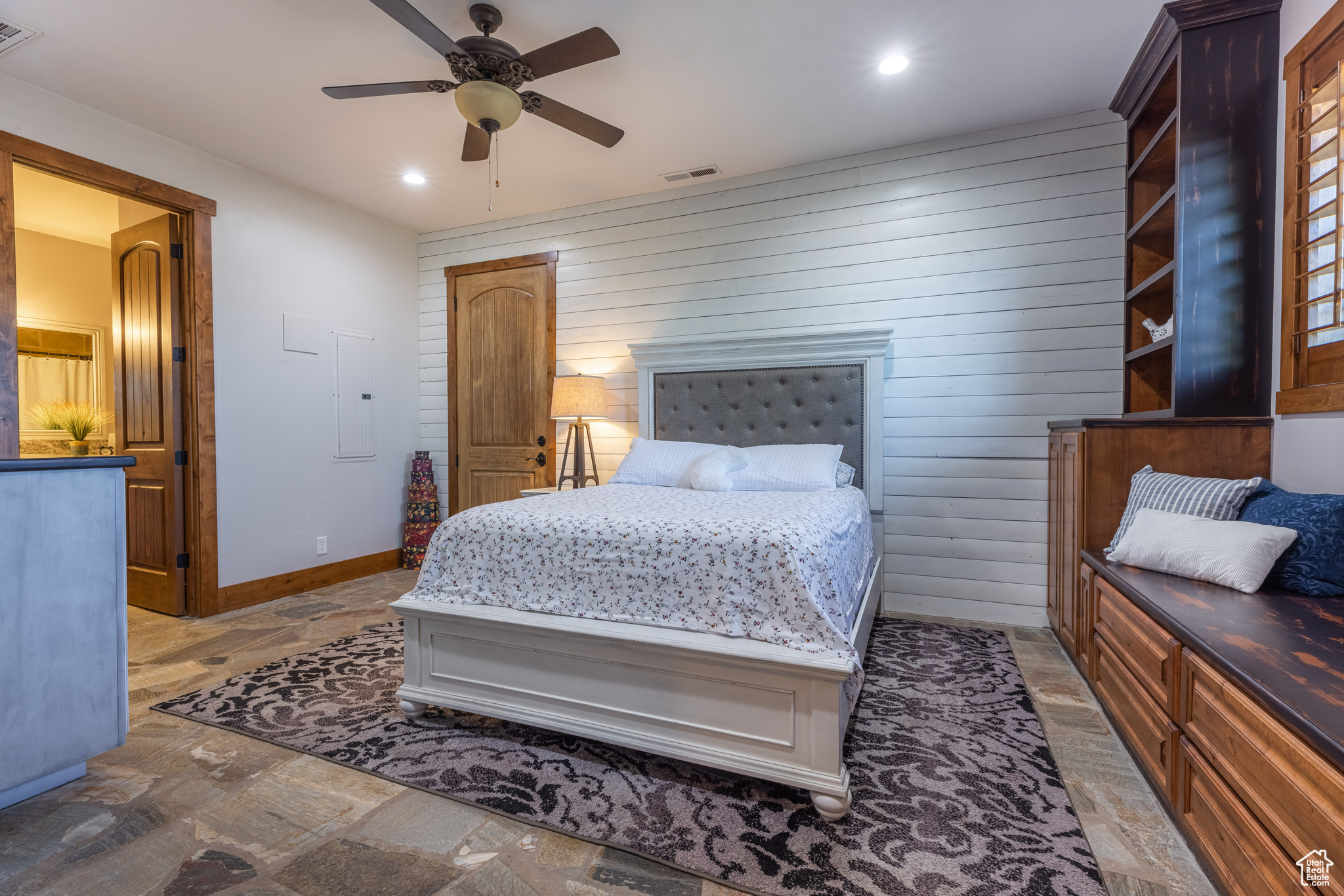 Bedroom with custom woodwork details including wood walls and ceiling fan
