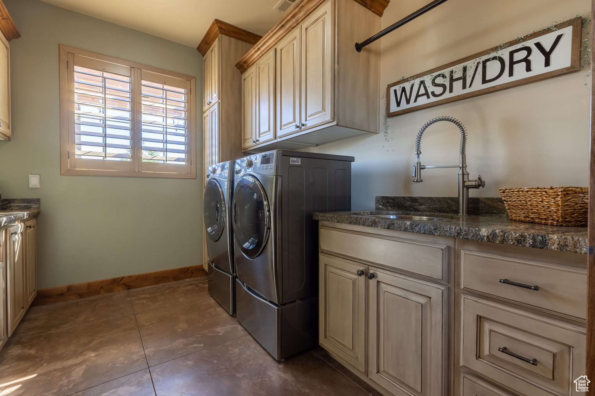 Washroom featuring cabinets, sink, dark tile flooring, and washer and dryer