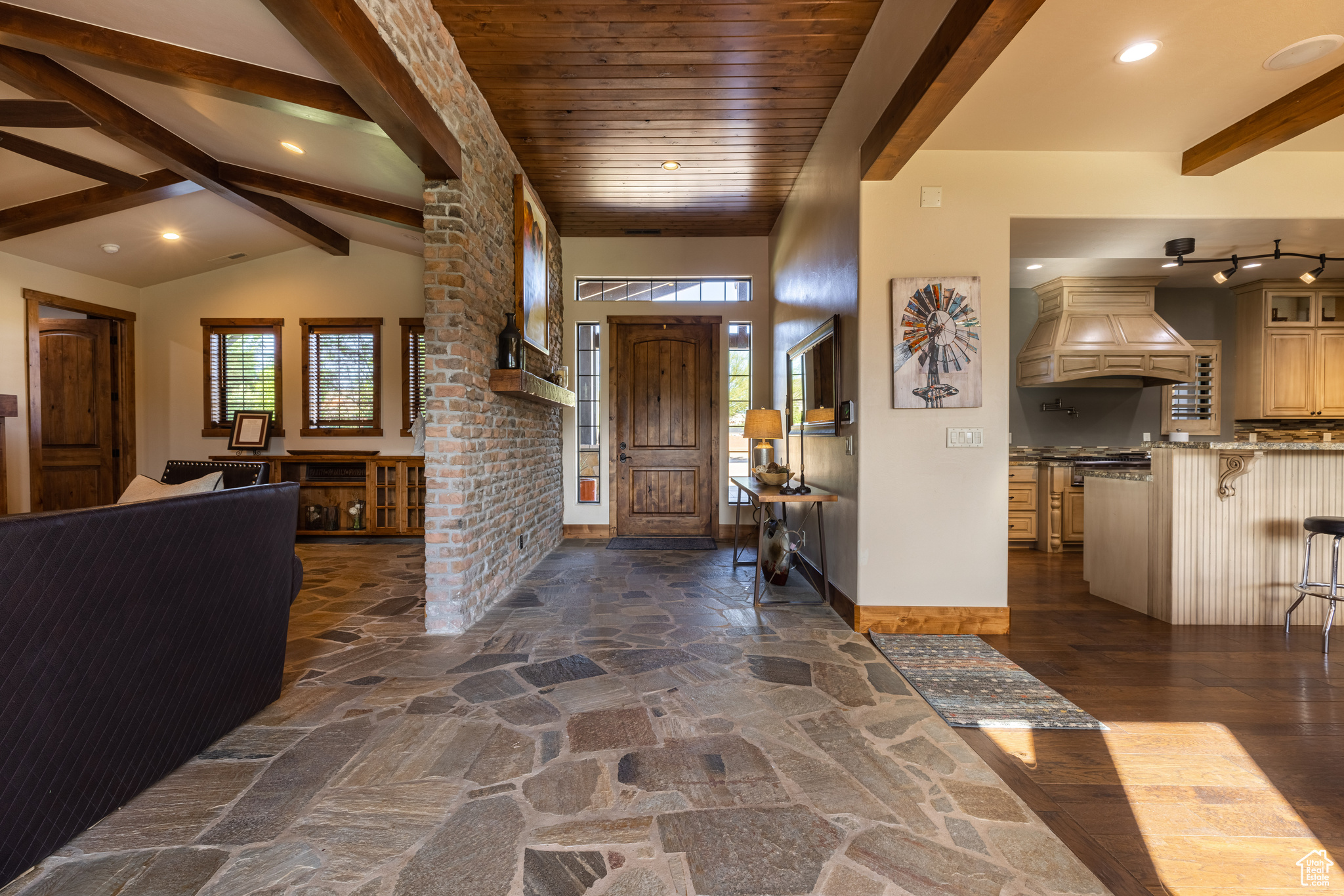 Entrance foyer with a wealth of natural light, Nevada slate flooring, and vaulted ceiling with beams in adjacent great room
