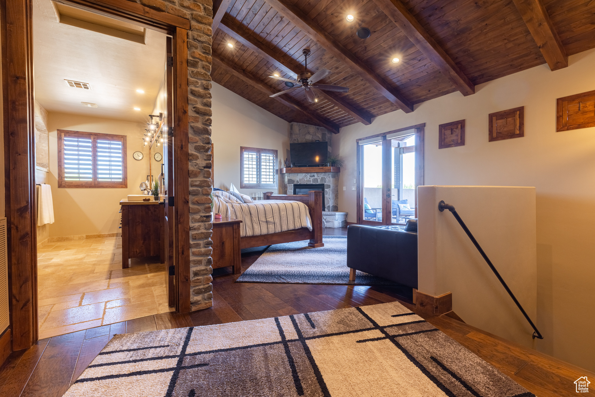 Principle bedroom suite with high vaulted ceiling, wooden ceiling, beam ceiling, and a stone fireplace