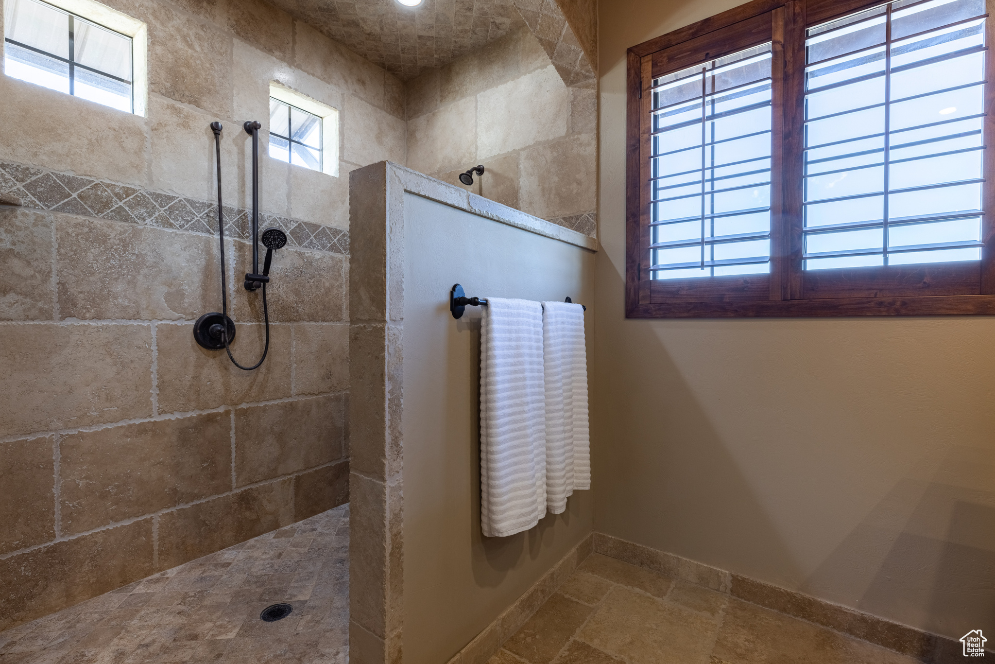 Principle suite Bathroom featuring tile flooring, tiled shower, and a wealth of natural light