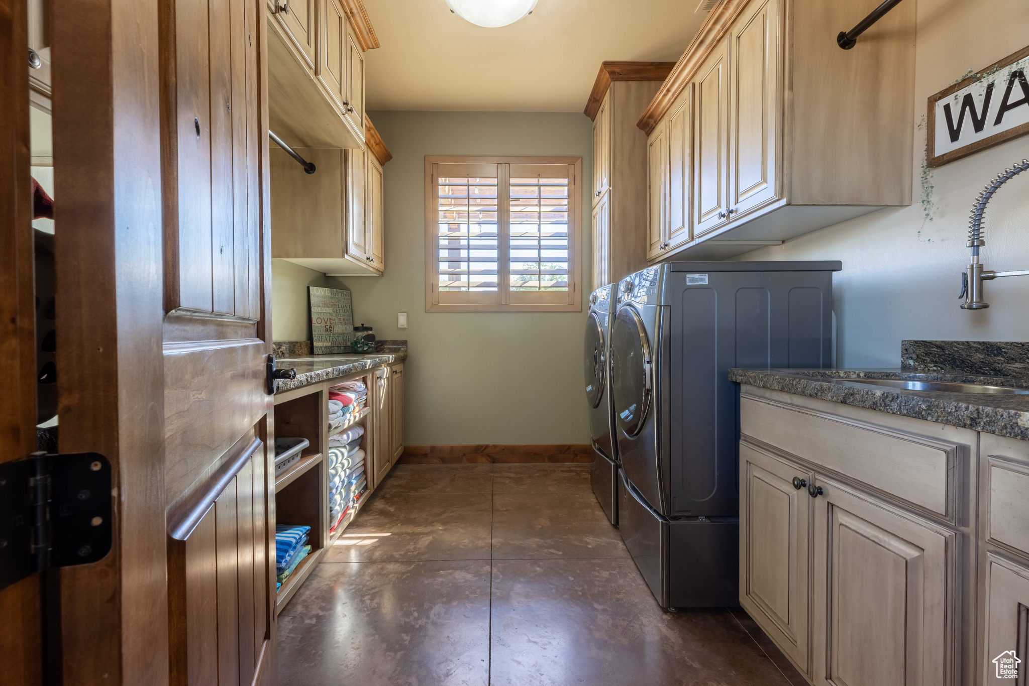 Laundry area with dark tile flooring, washing machine and clothes dryer, and cabinets