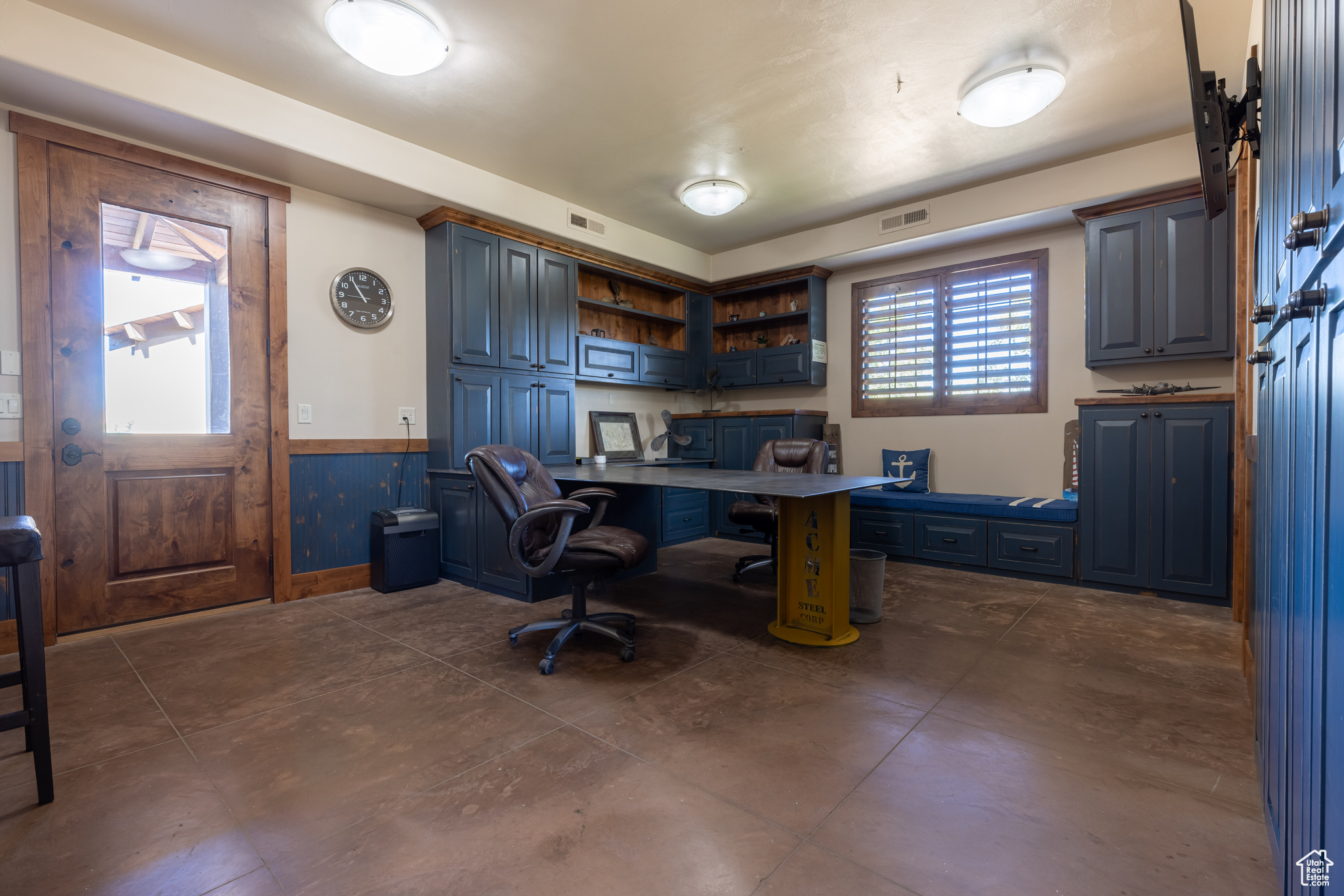 Home office featuring plenty of natural light and dark tile floors, buildt ins with a steel desk!