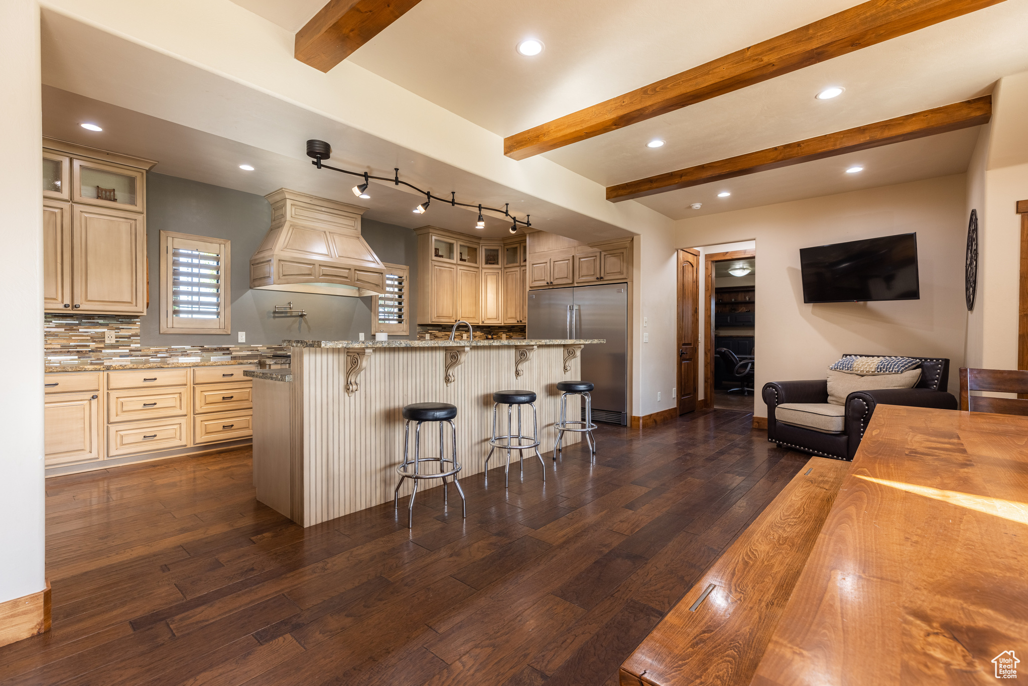 Kitchen with built in refrigerator, light stone countertops, custom range hood, dark hardwood / wood-style floors, and beam ceiling