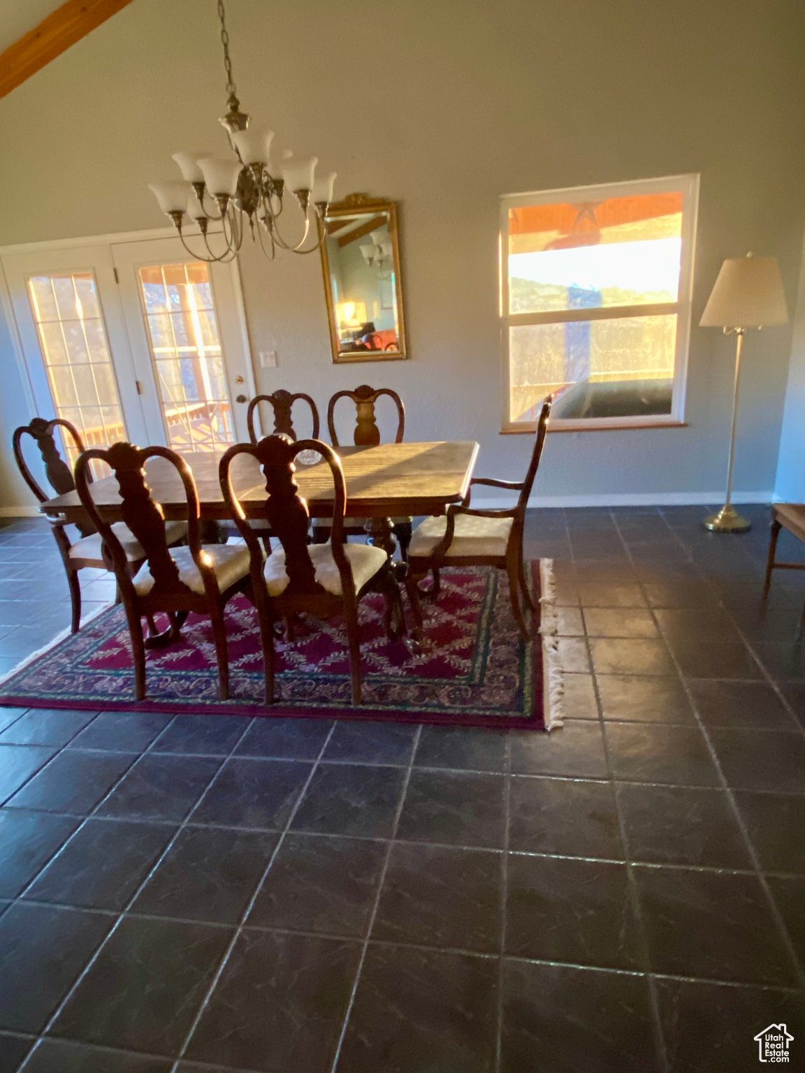 Tiled dining room featuring plenty of natural light, high vaulted ceiling, and a notable chandelier