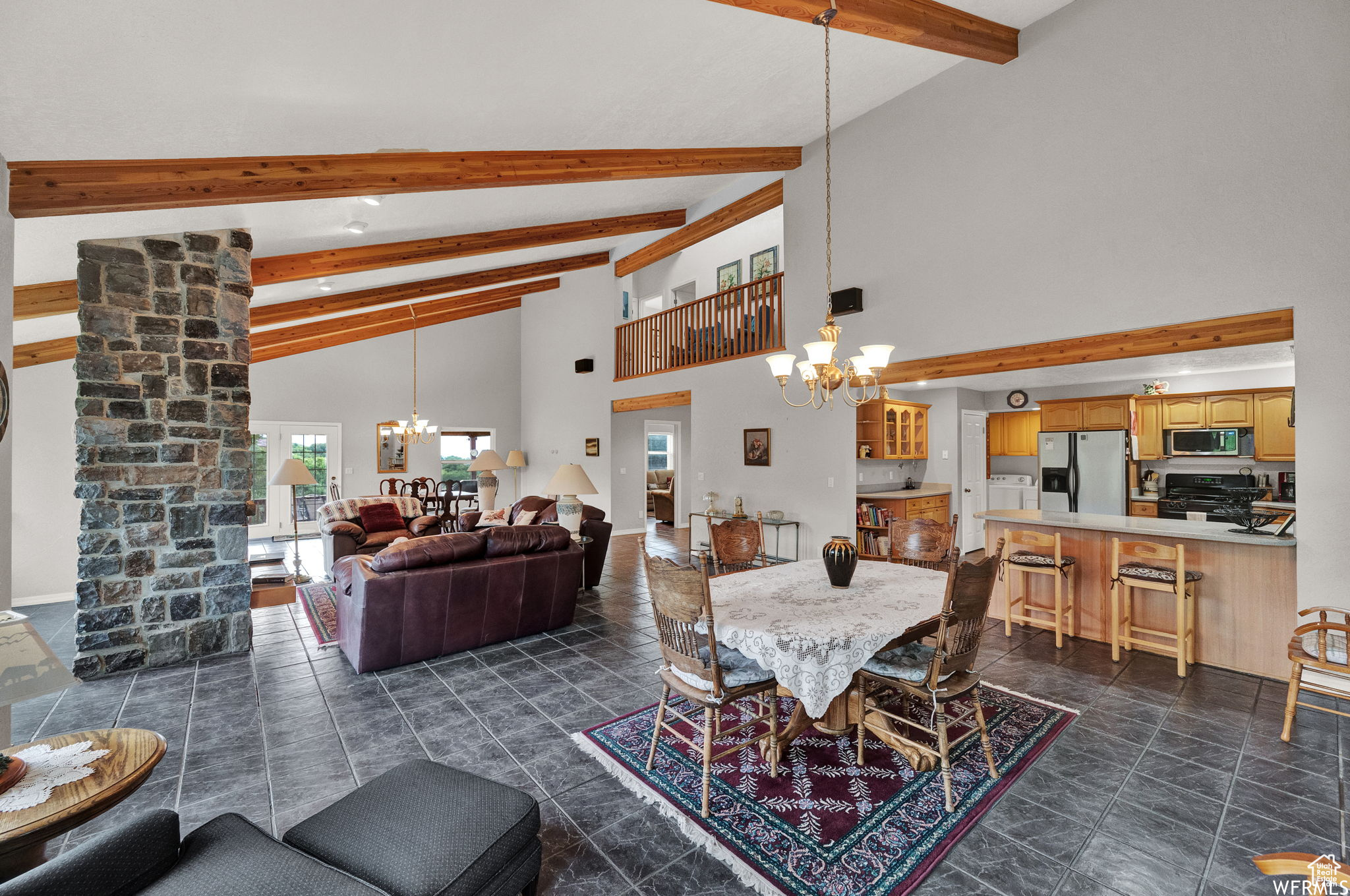 Tiled dining area featuring a notable chandelier, ornate columns, high vaulted ceiling, and beam ceiling