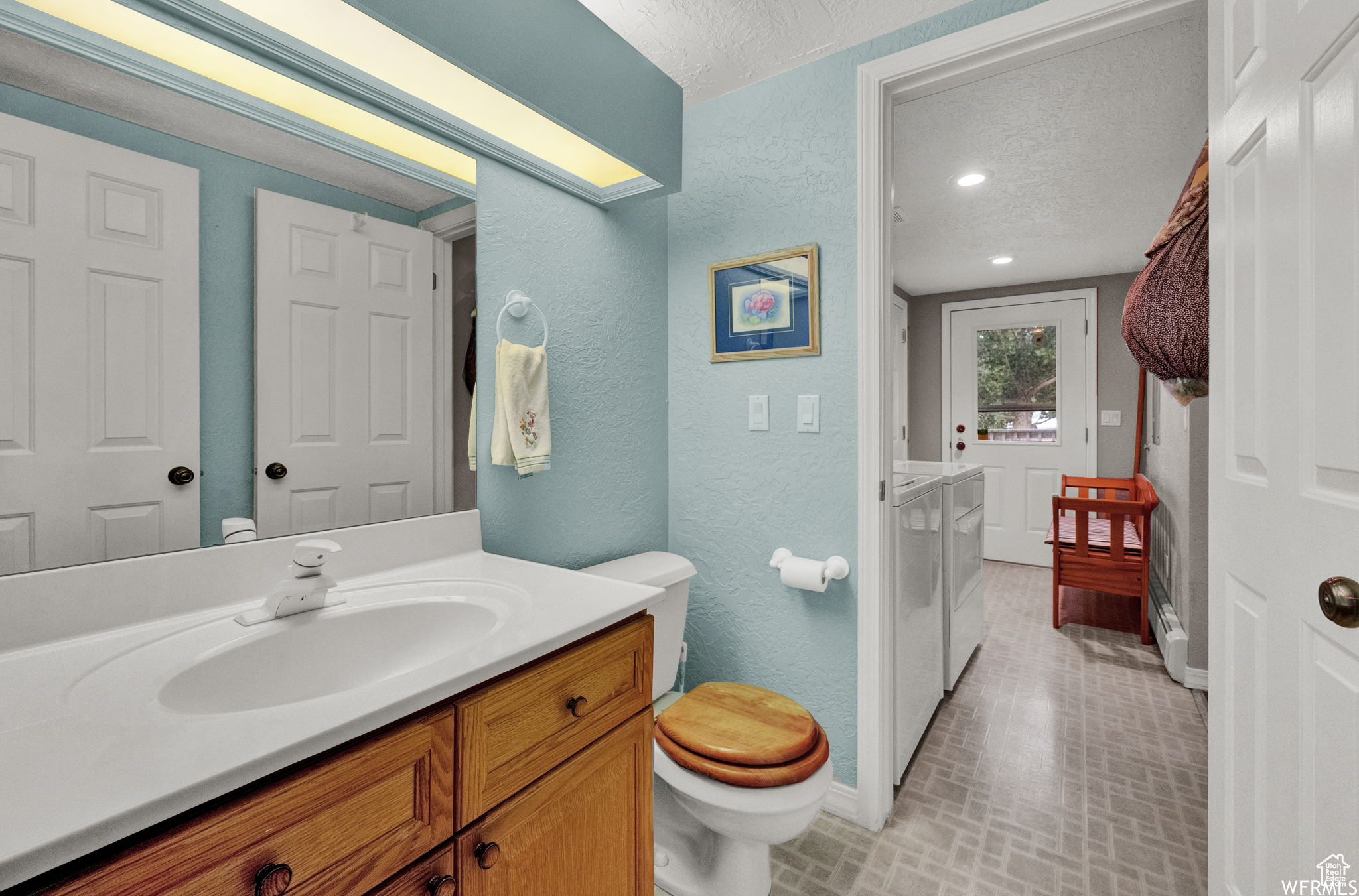 Bathroom featuring tile floors, vanity with extensive cabinet space, a textured ceiling, and toilet