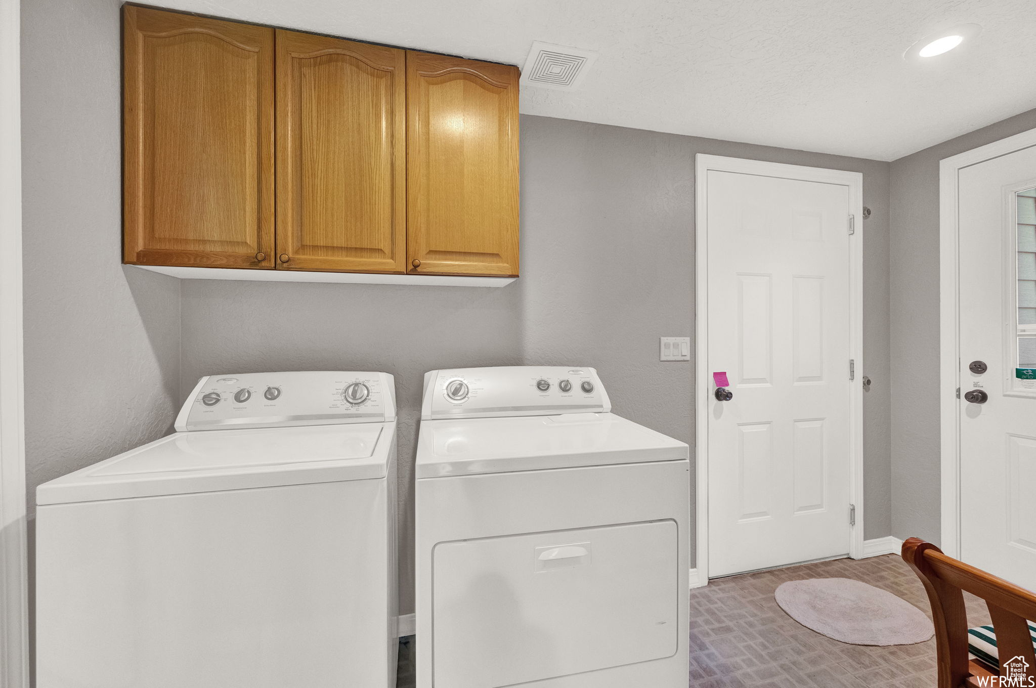 Clothes washing area with cabinets and separate washer and dryer