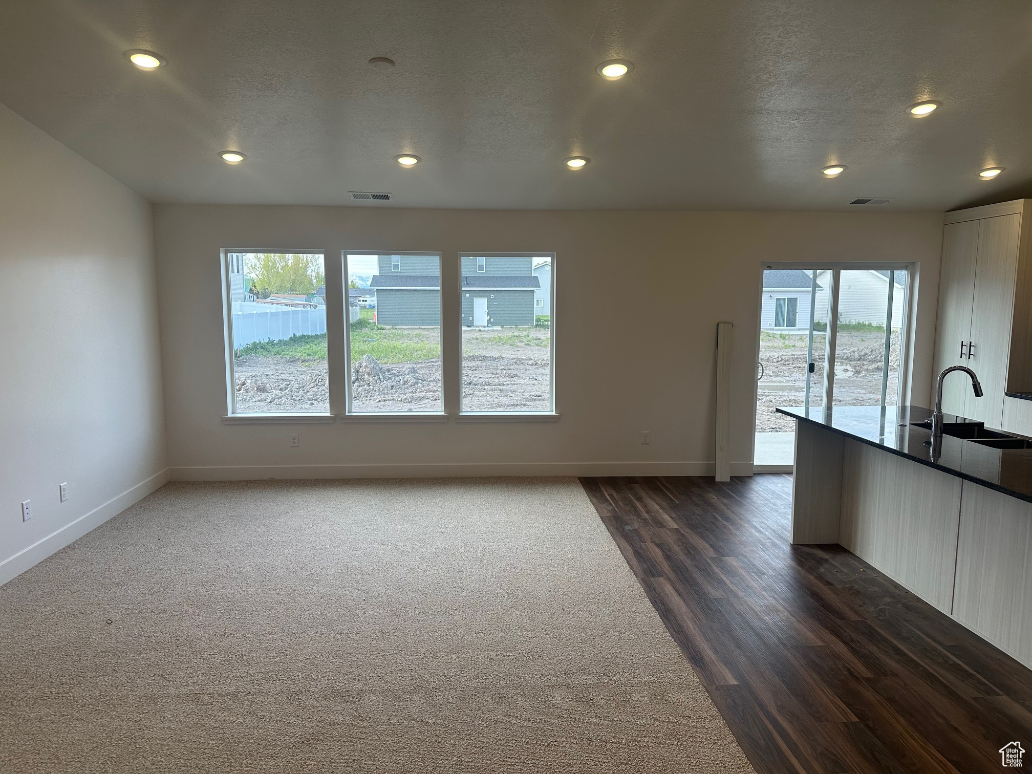 Unfurnished living room with dark colored carpet, a wealth of natural light, and sink