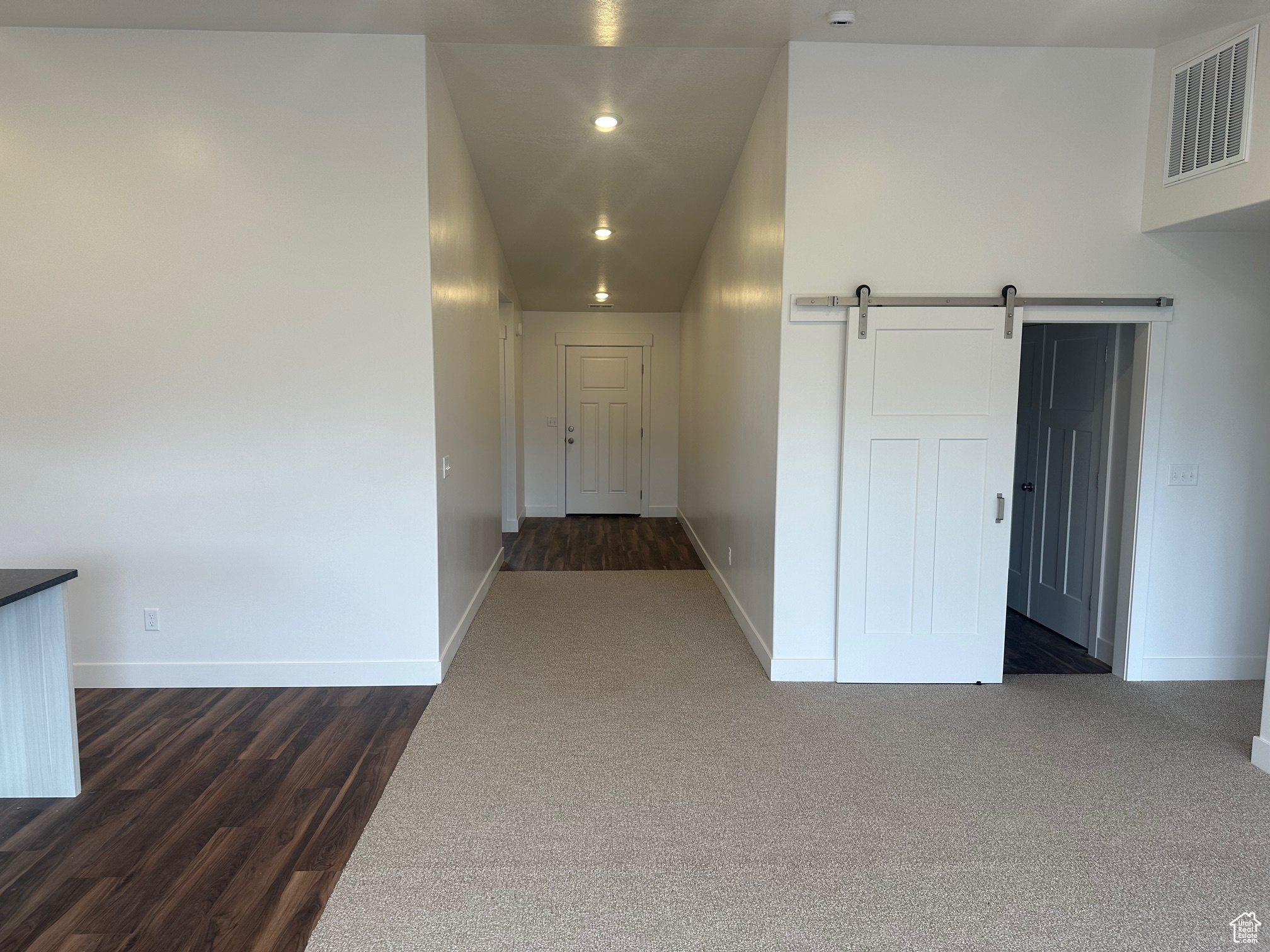 Hallway with a barn door and dark wood-type flooring