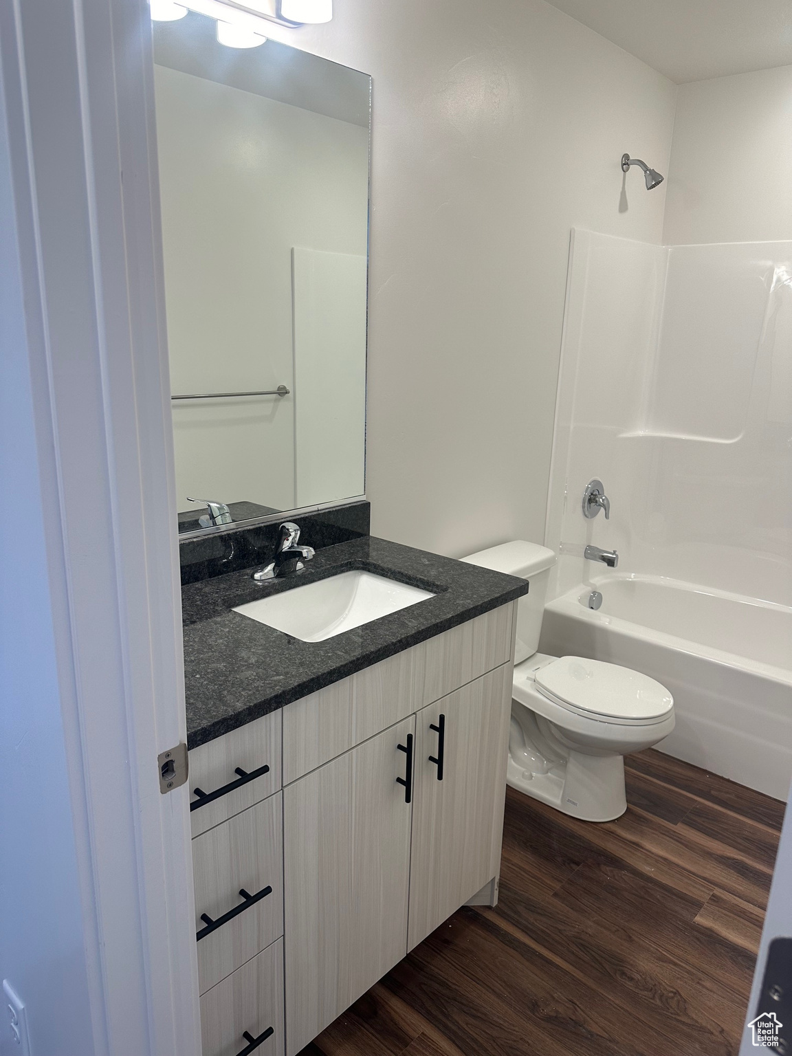 Full bathroom with  shower combination, hardwood / wood-style floors, toilet, and vanity