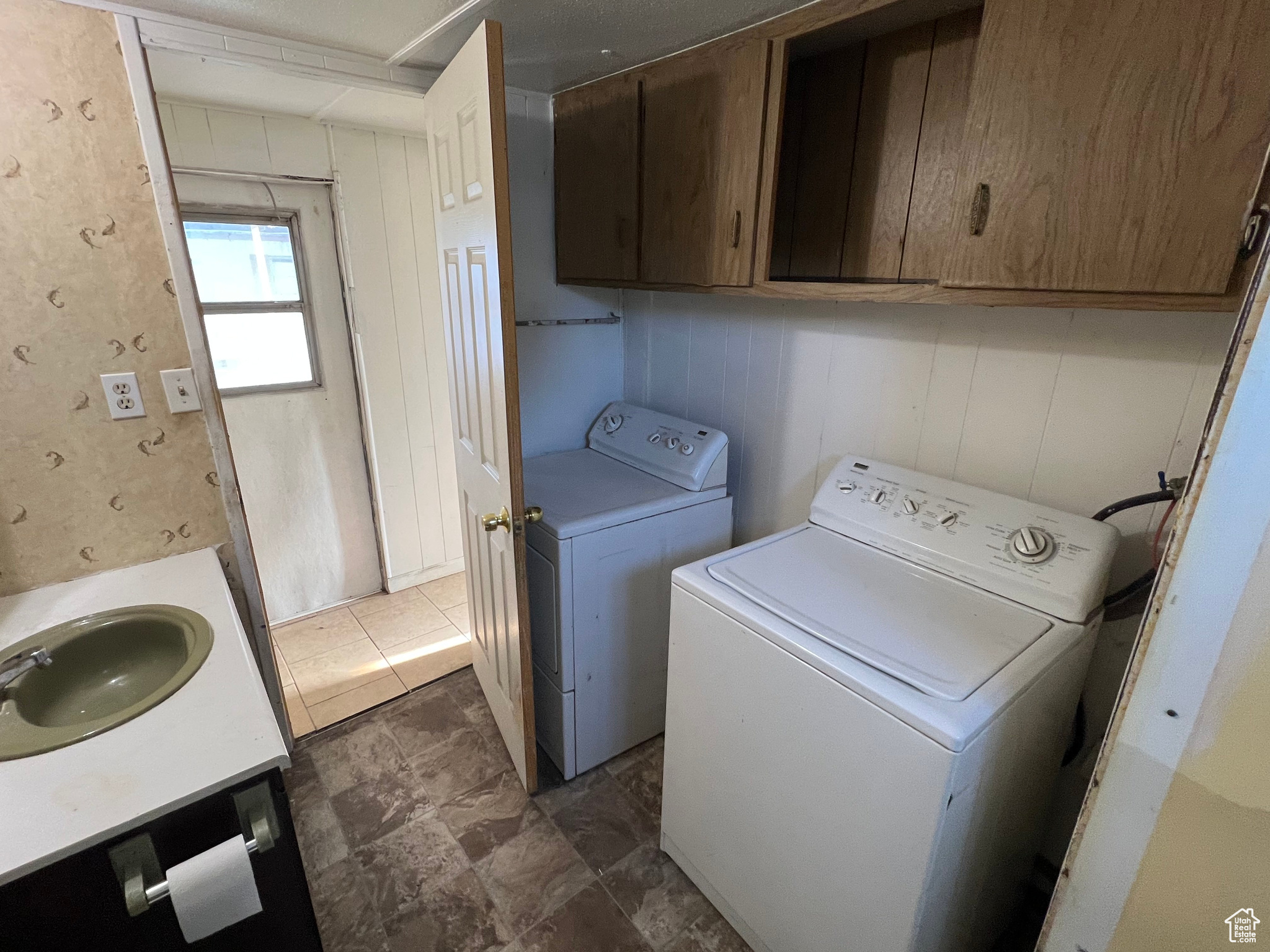 Clothes washing area featuring separate washer and dryer, sink, and dark tile flooring