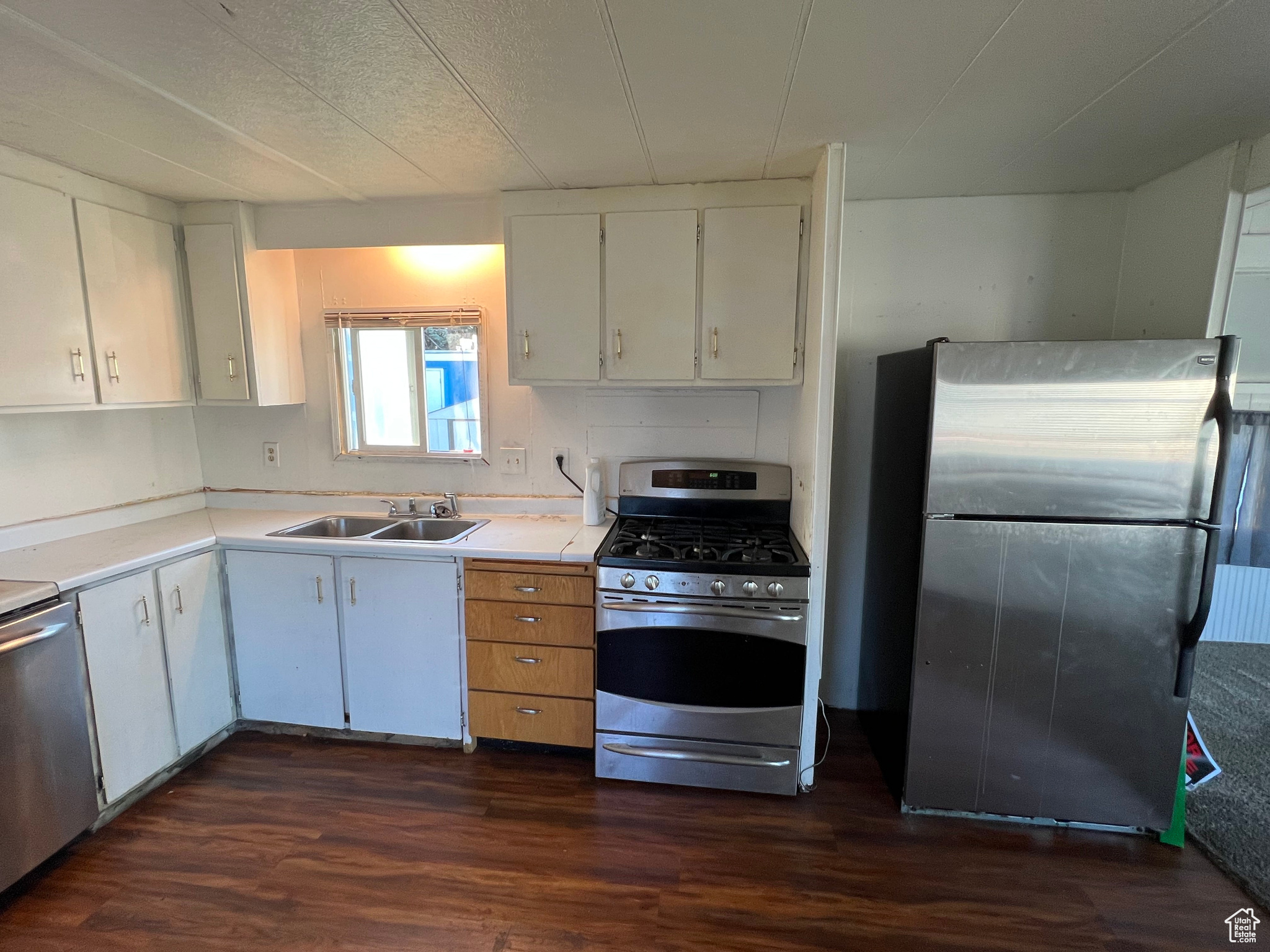 Kitchen with white cabinets, sink, dark wood-type flooring, and stainless steel appliances