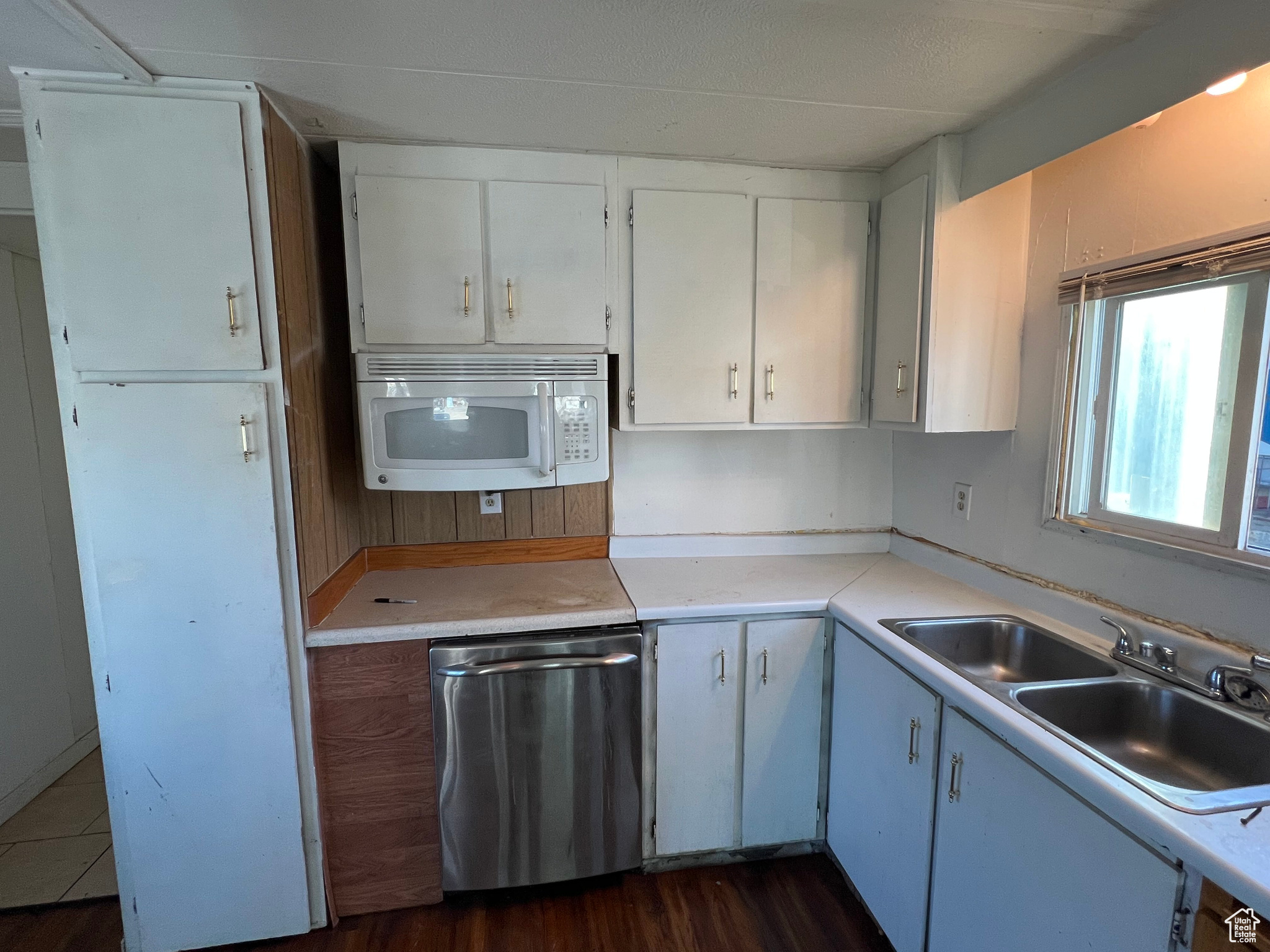 Kitchen featuring dishwasher, sink, white cabinetry, and dark hardwood / wood-style floors