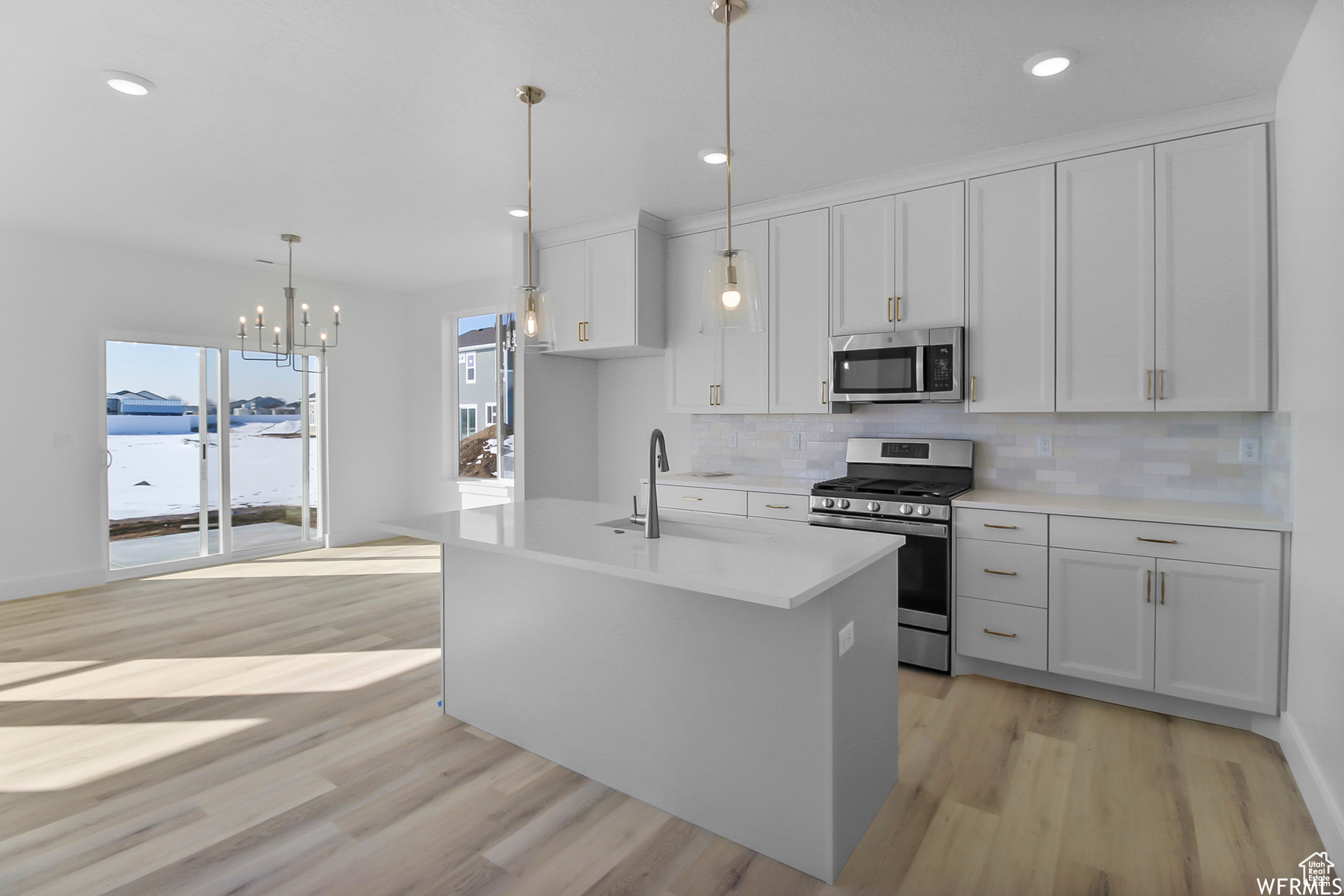 Kitchen featuring backsplash, appliances with stainless steel finishes, sink, and light wood-type flooring